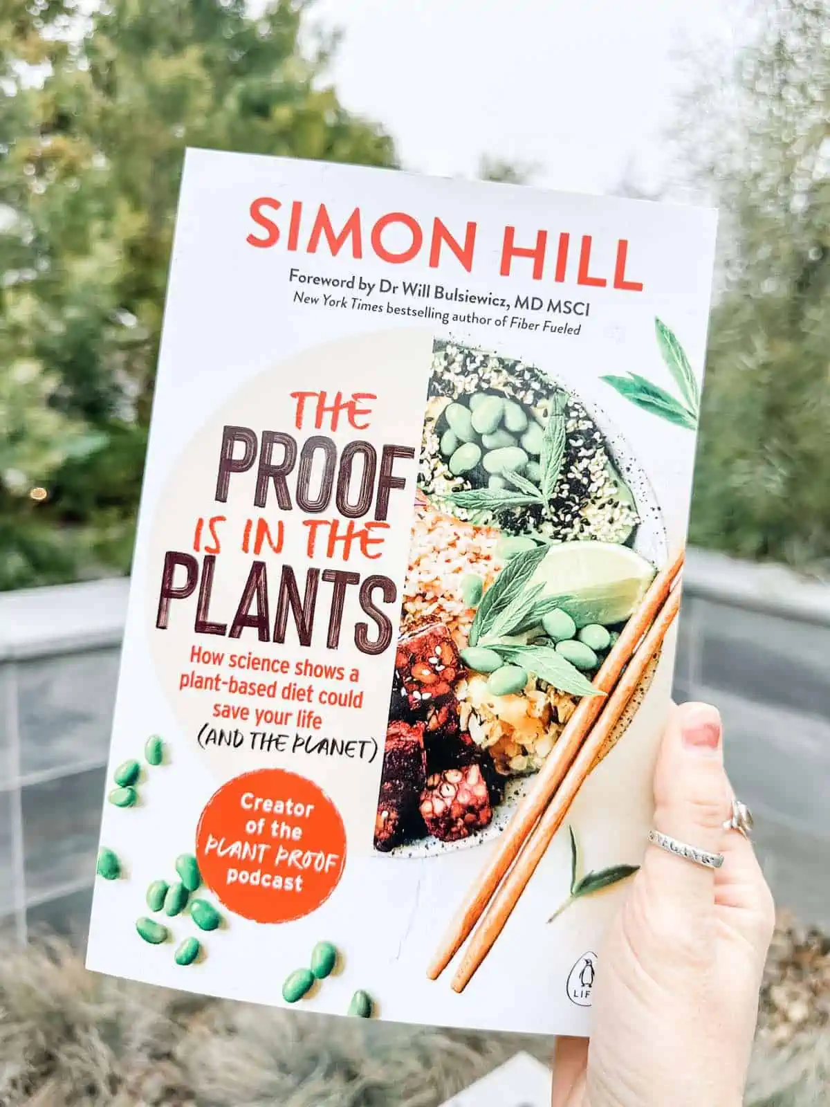 Vegan woman holding out Simon Hill's book The Proof is in the Plants.