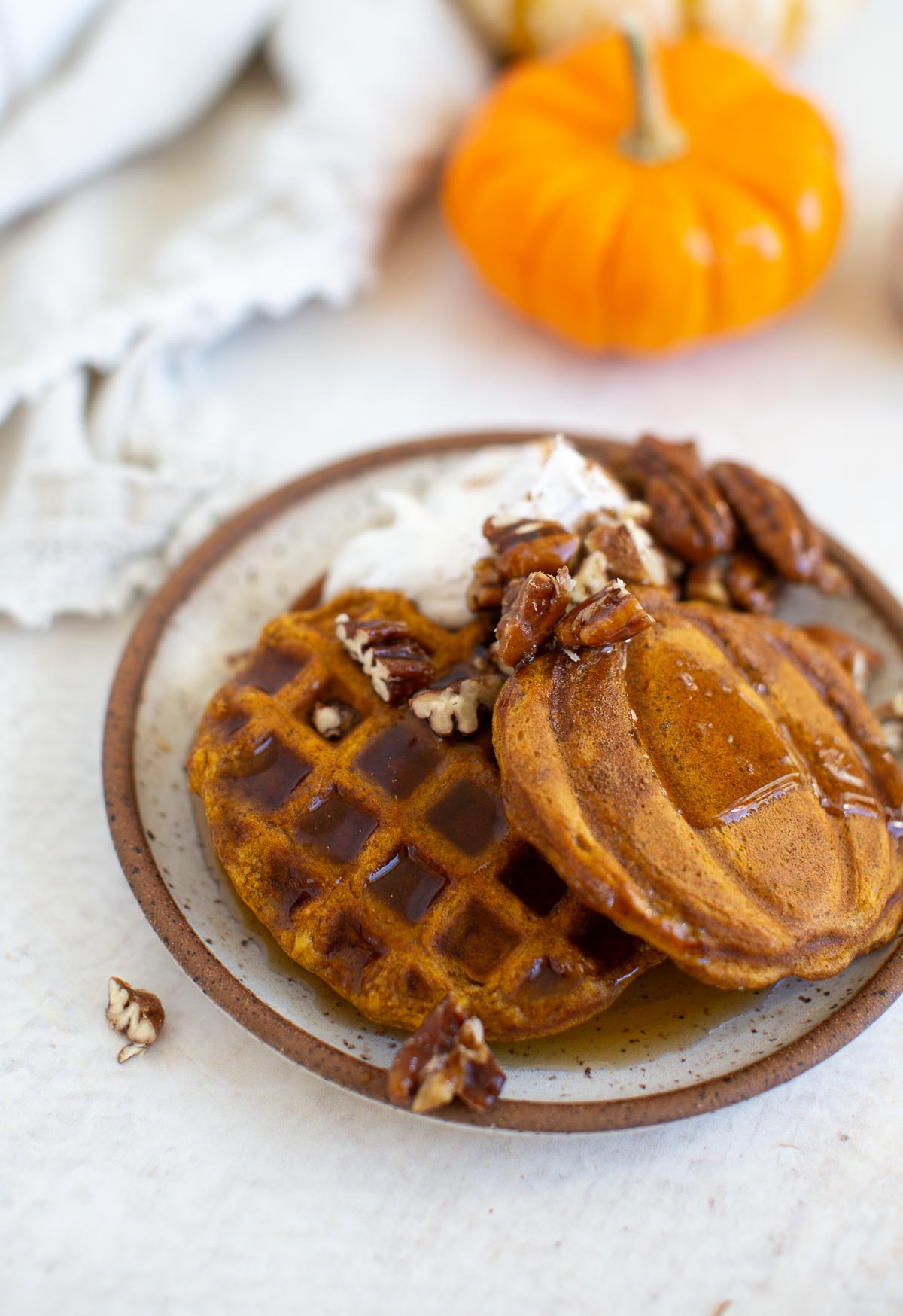 Vegan pumpkin waffles served with pumpkin pancakes, maple syrup, candied pecans, and whipped cream.