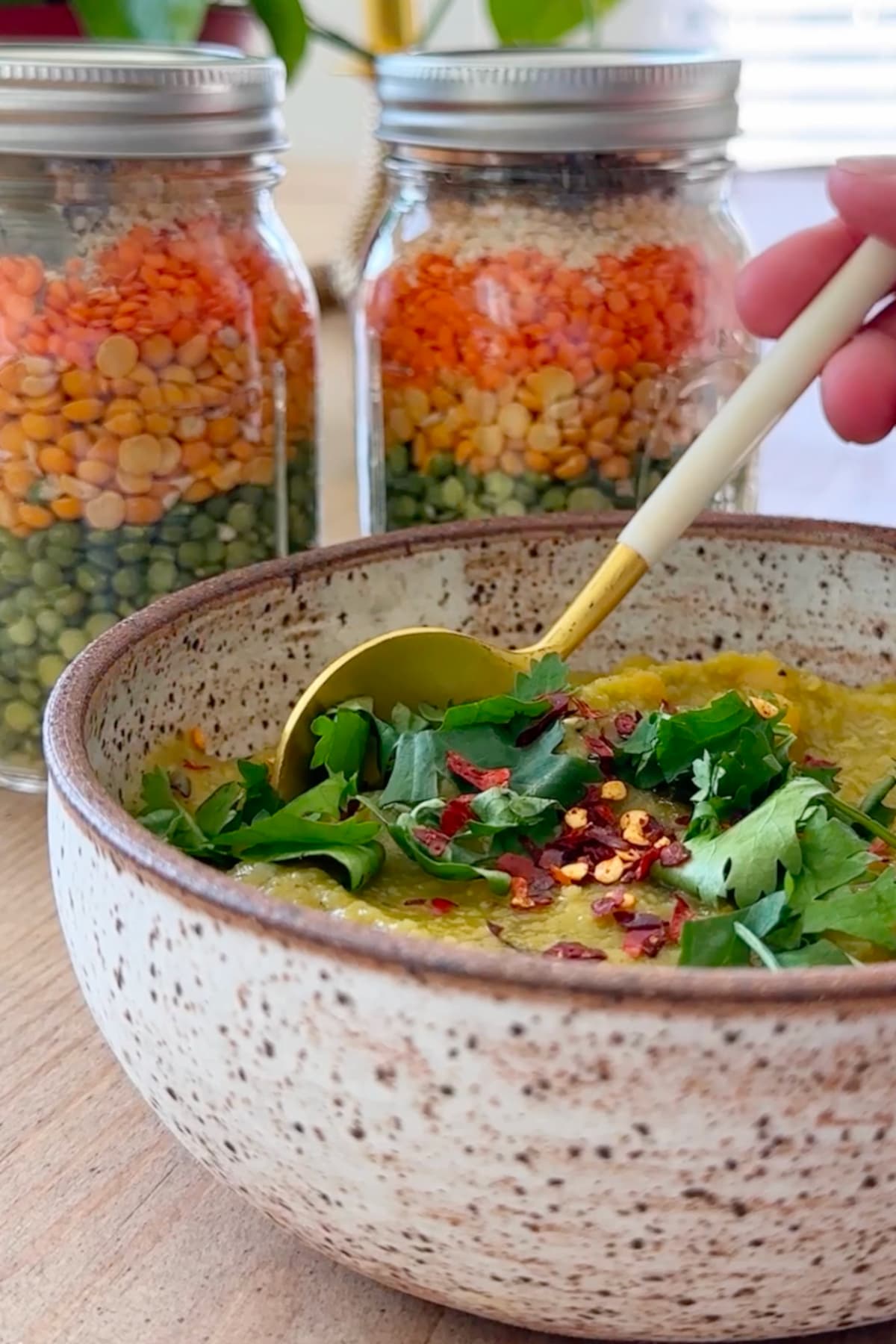A bowl of split pea lentil soup next to jars of soup mix.