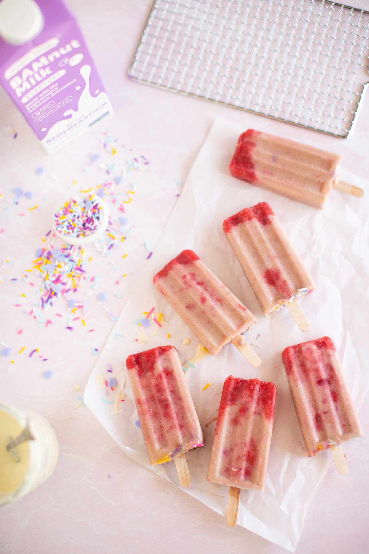 Plant-based milk, sprinkles, and strawberry popsicle ingredients.