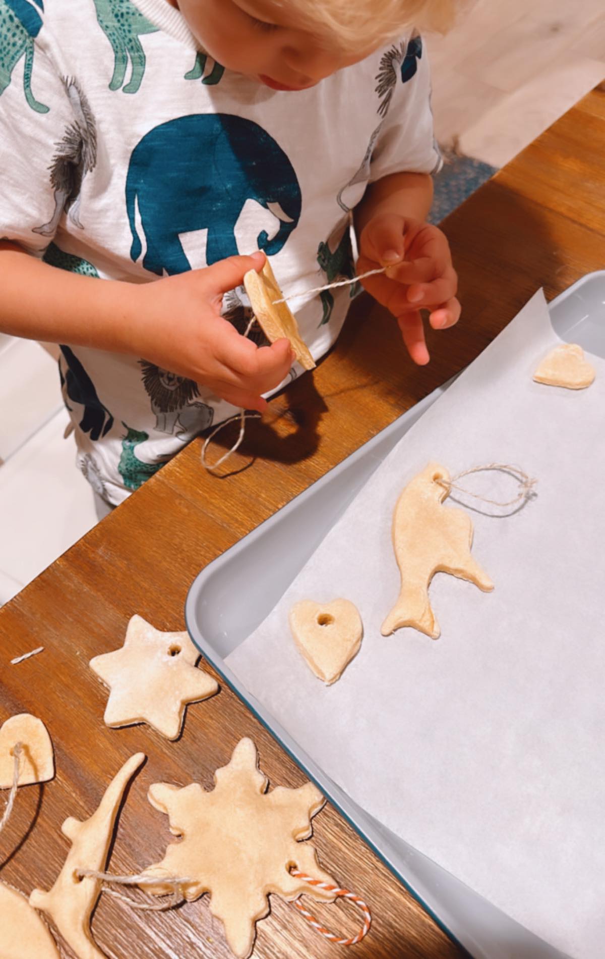 Vegan kid Graham Miller stringing holiday salt dough ornaments on a baking sheet.