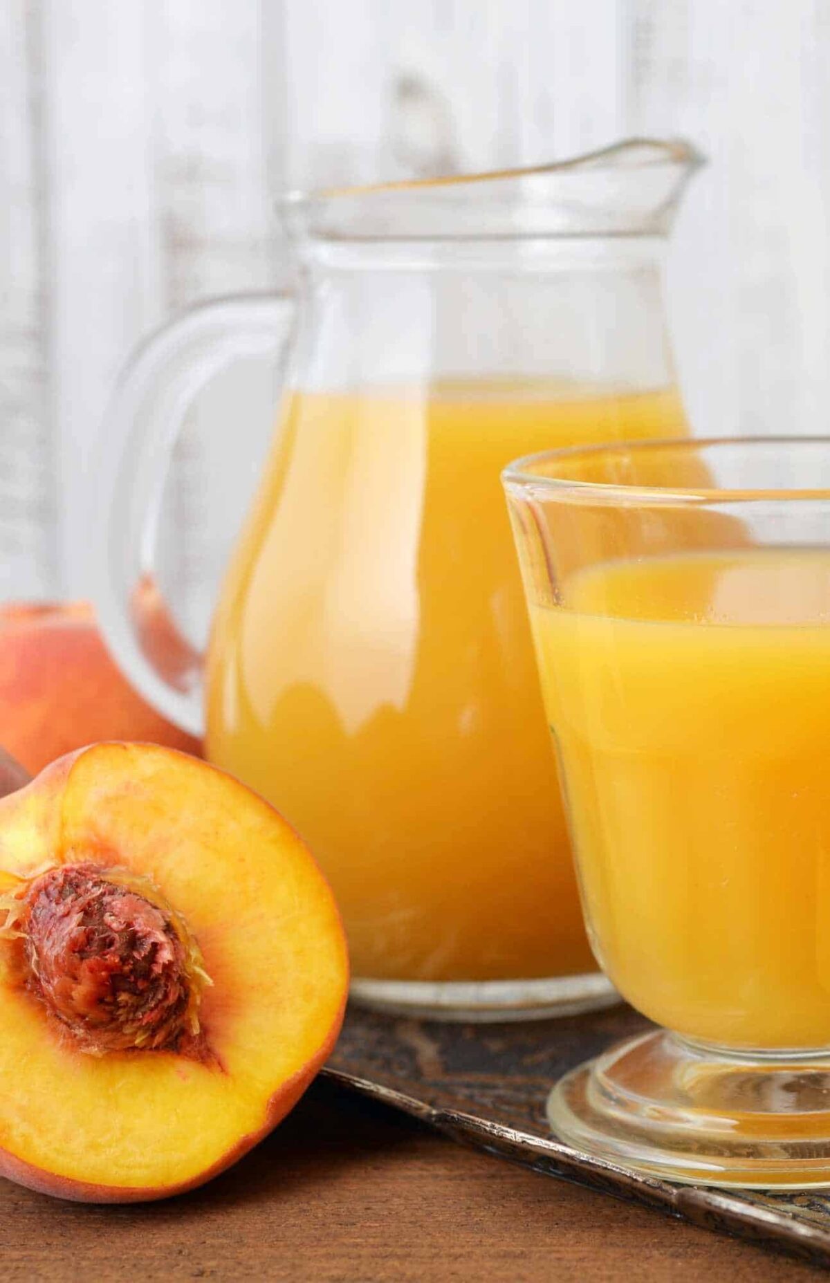 Large pitcher of fresh peach juice with lemon slices, great for brunch or summer cookouts.