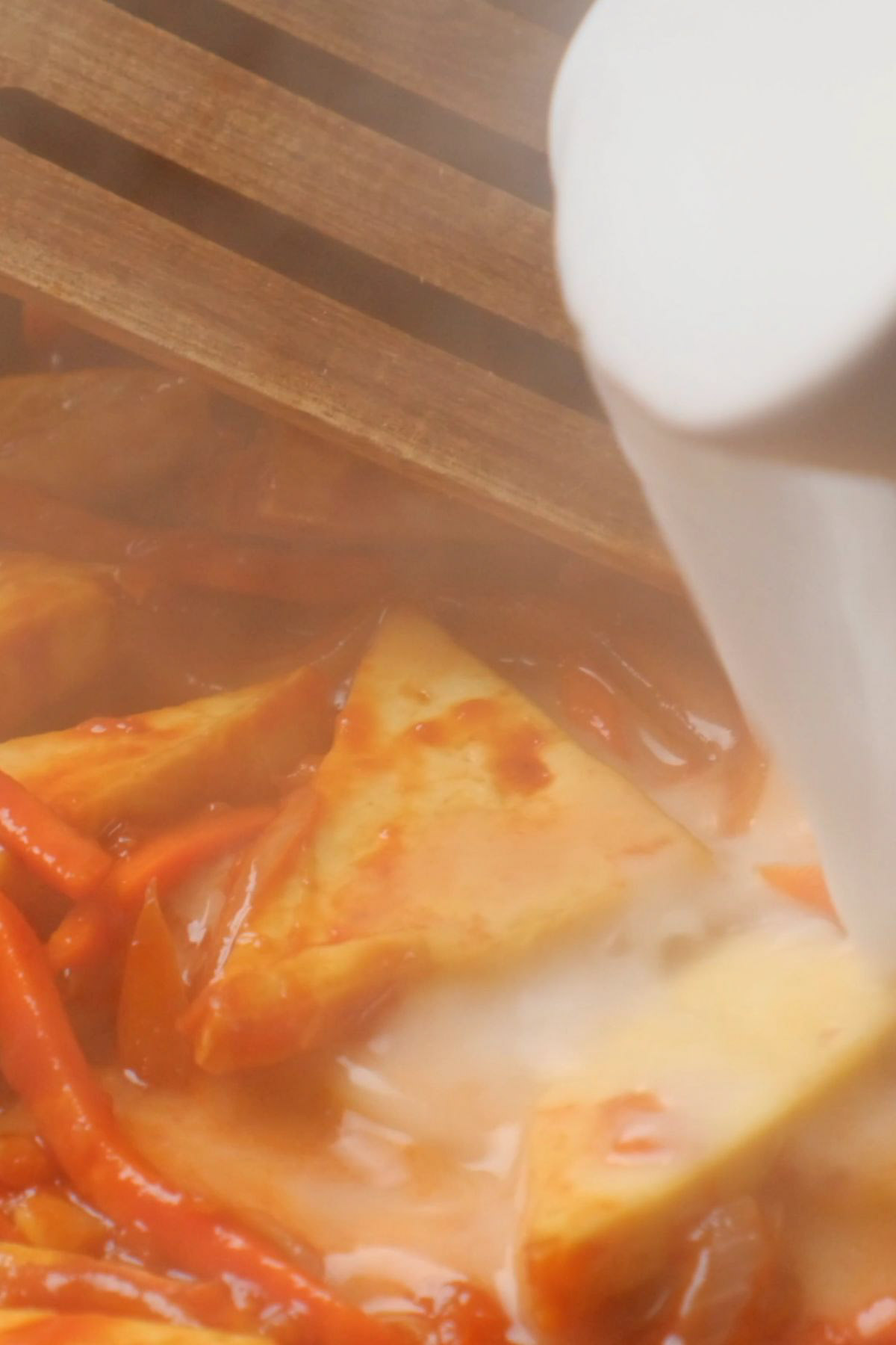 A cornstarch slurry being added to a skillet.
