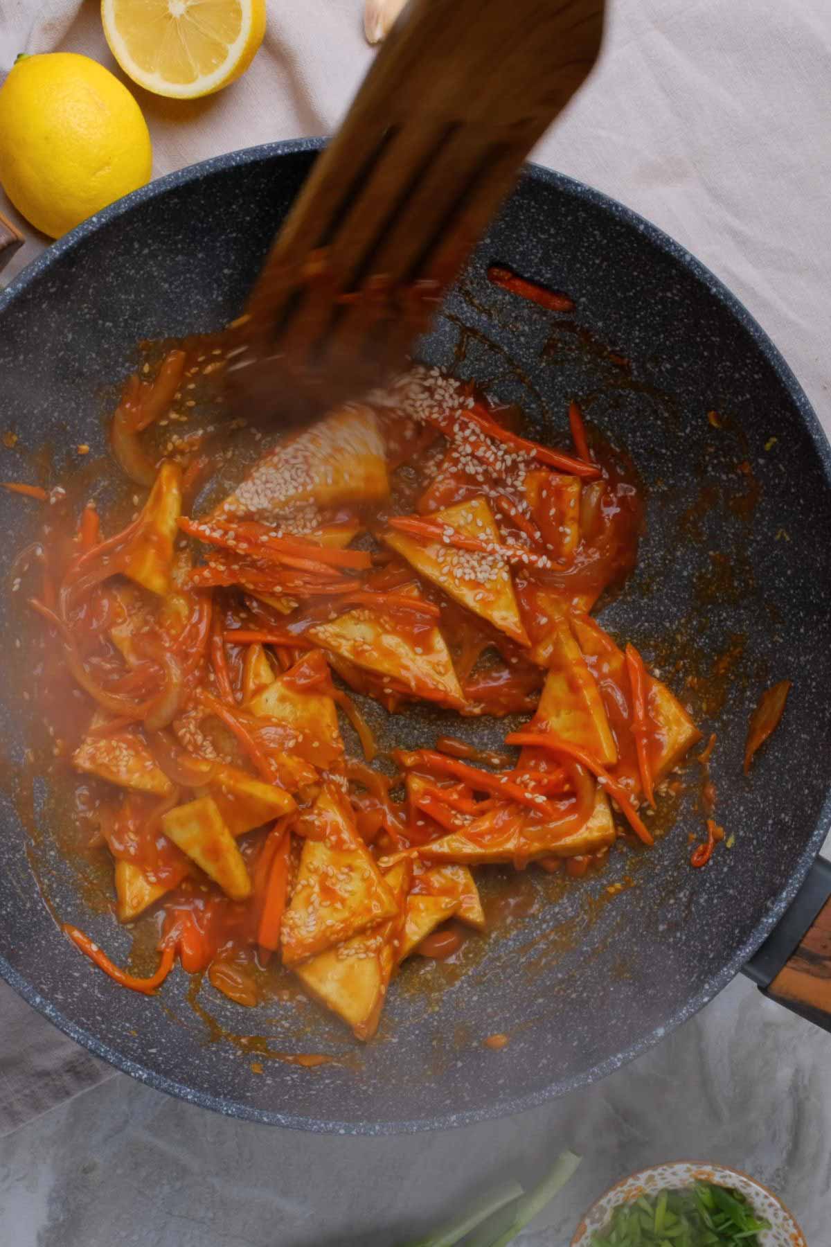 Sweet and sour tofu being cooked in a skillet.