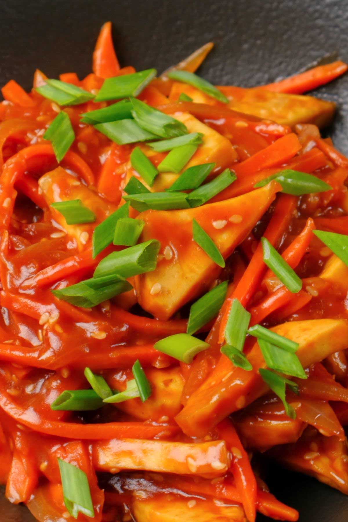 Sweet and sour tofu garnished with green onions.