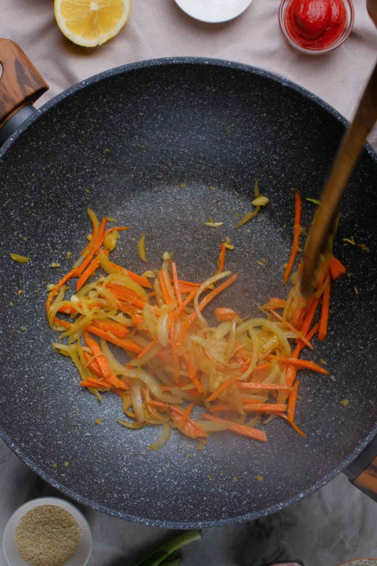 Cooked carrots, onions, and ginger in a skillet.