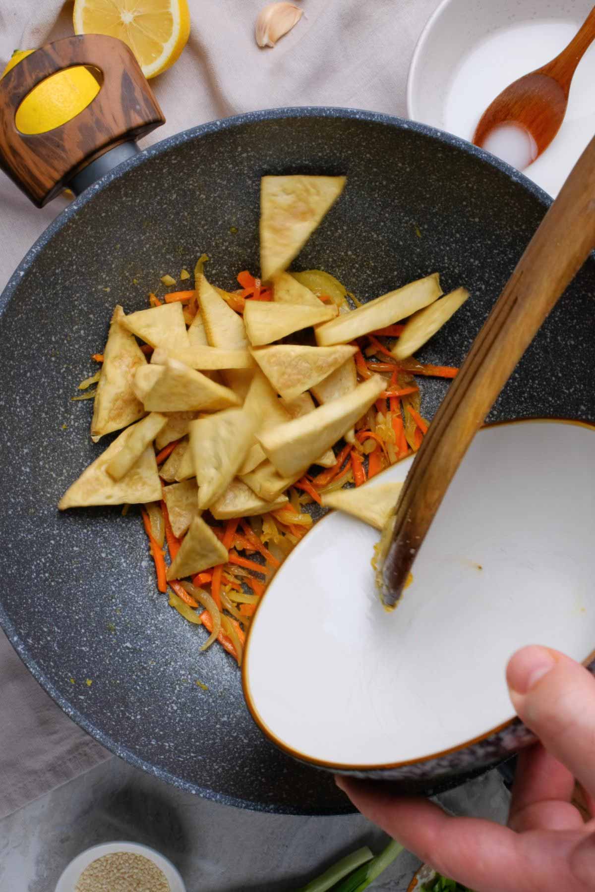 Tofu triangles in a skillet with onions.