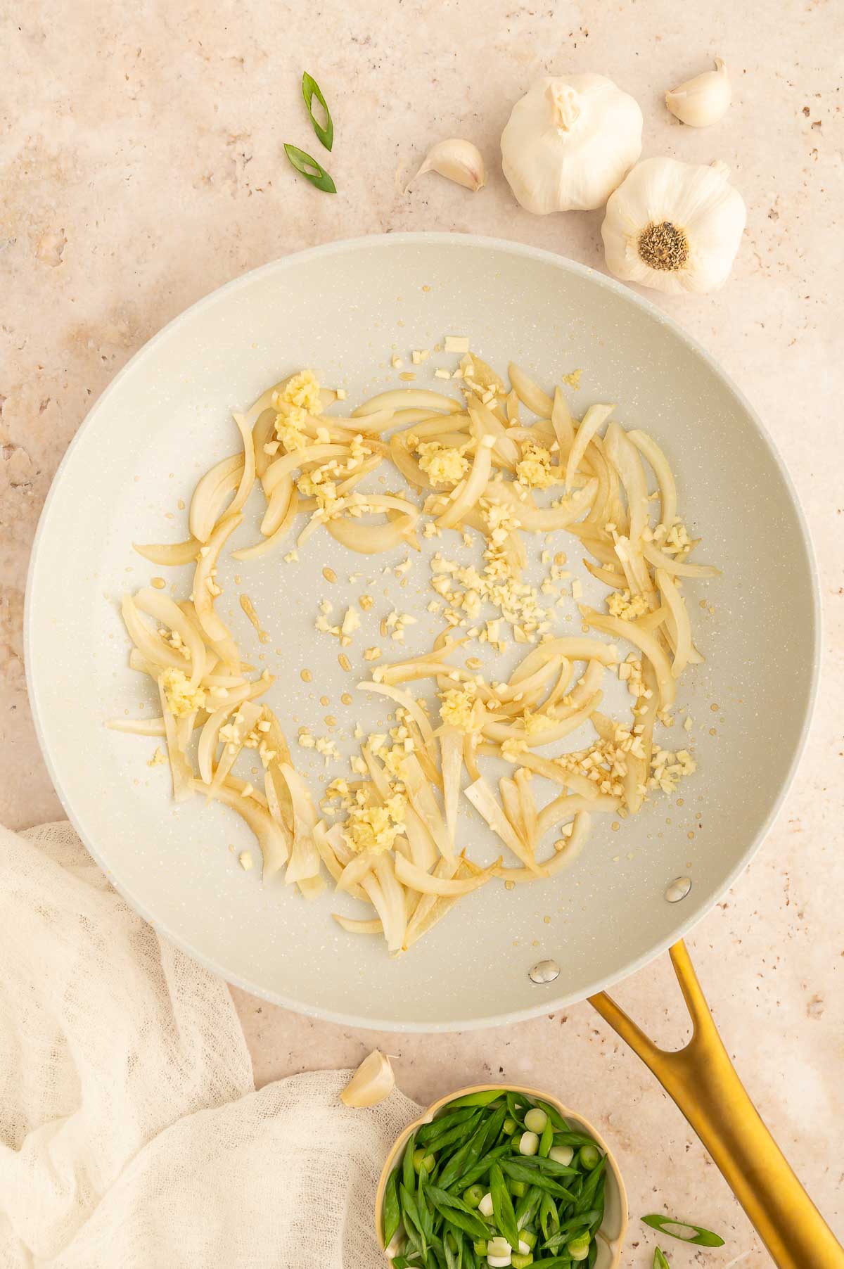 Garlic and onion sizzling in a skillet for the start of a veggie stir fry.