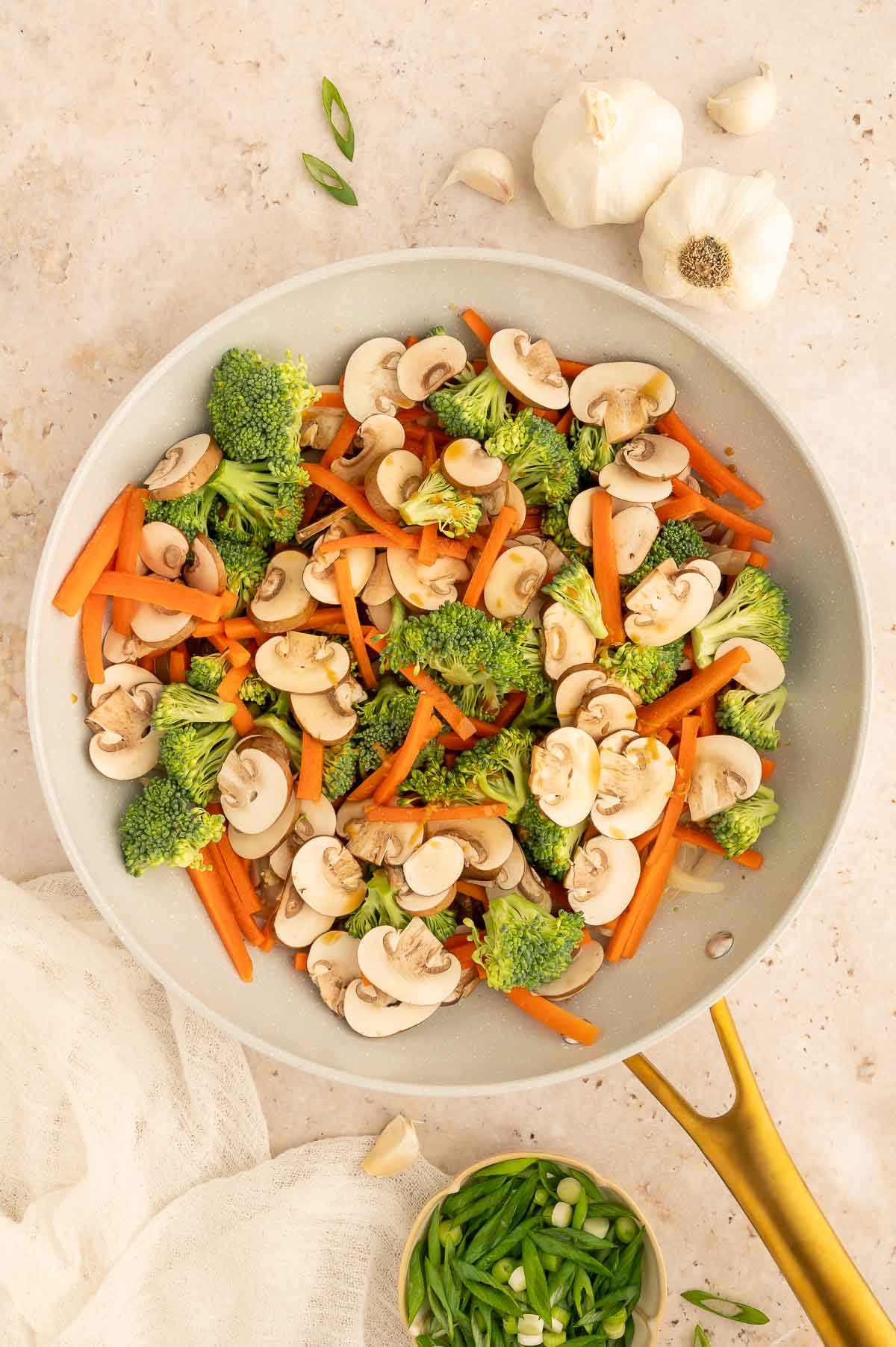 Broccoli, mushrooms, and carrots tossed in a pan for vegetable stir fry.