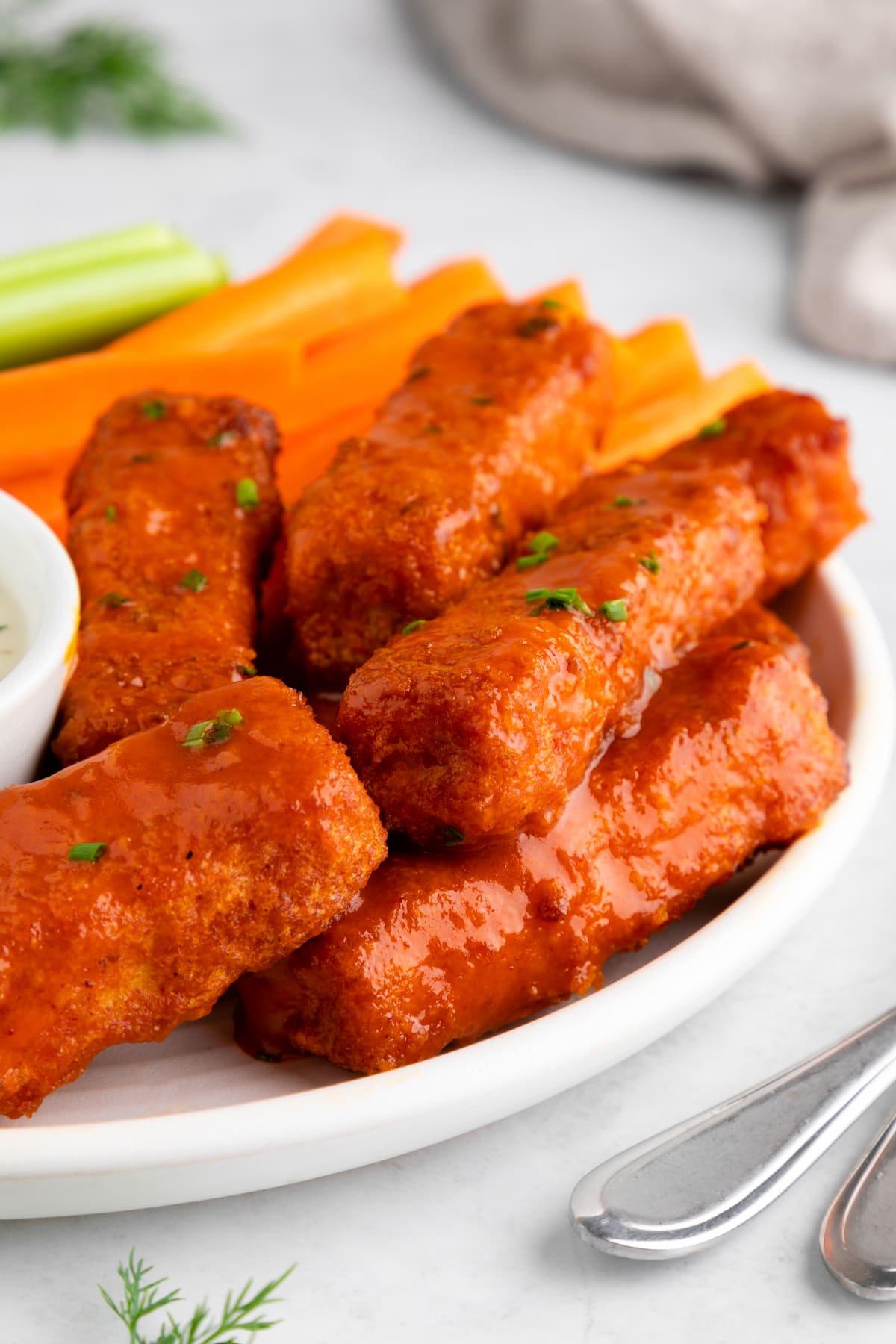 Tofu buffalo wings on a plate with a sprinkle of fresh herbs on top.