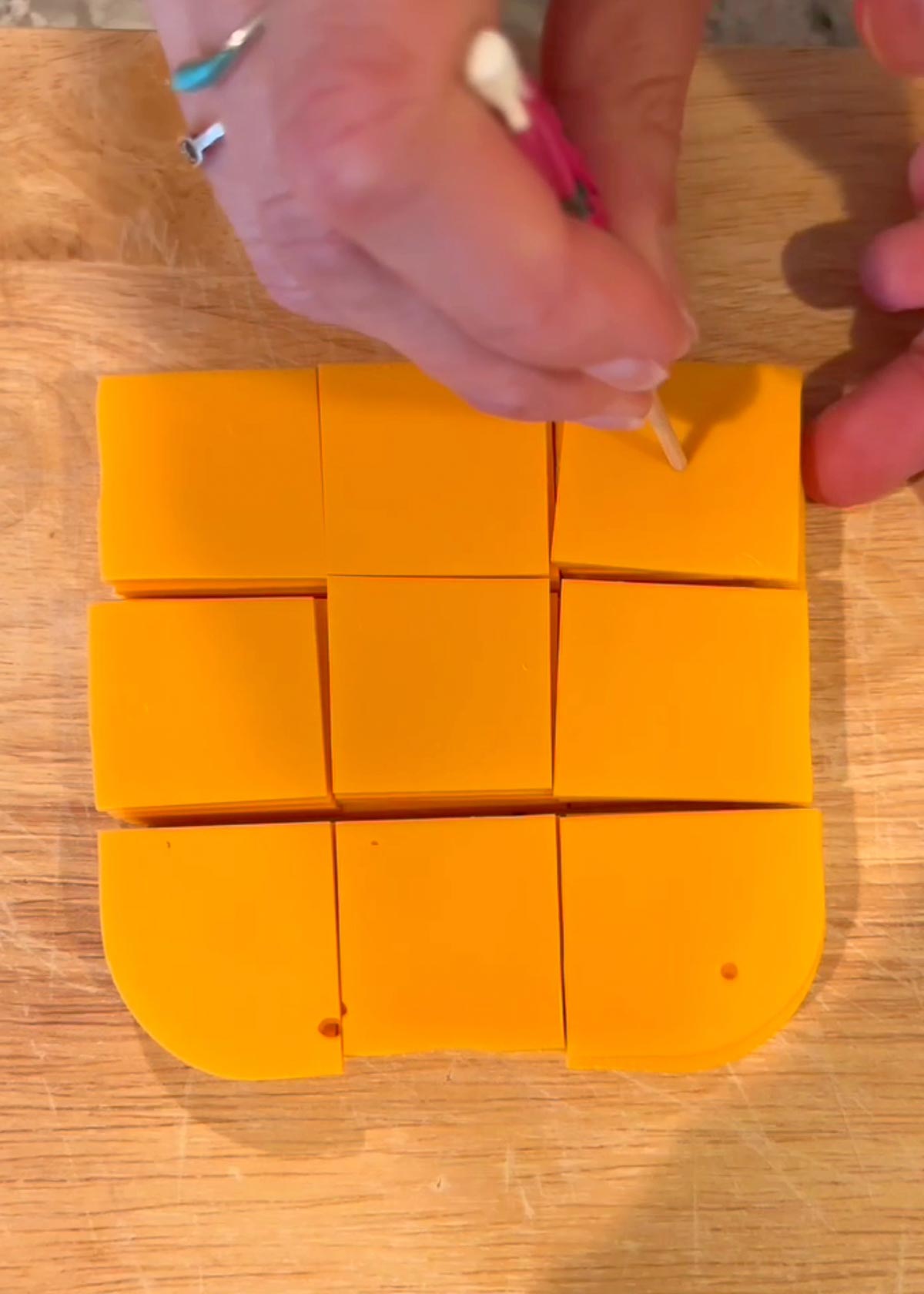 Poking holes in the vegan cheez its made from cheddar slices using a toothpick.