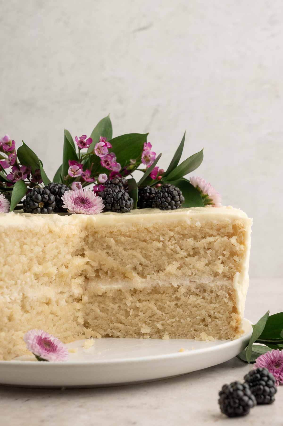 A slice of cake with blackberries and flowers.