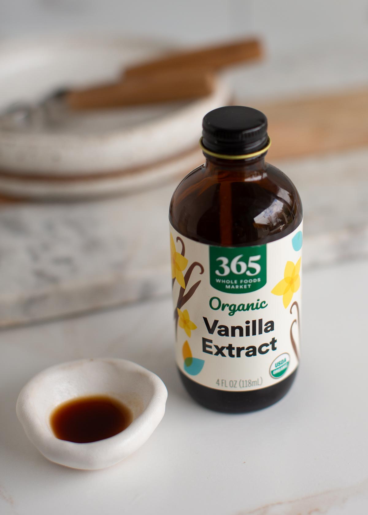 Vanilla extract bottle next to a small bowl of vanilla extract.