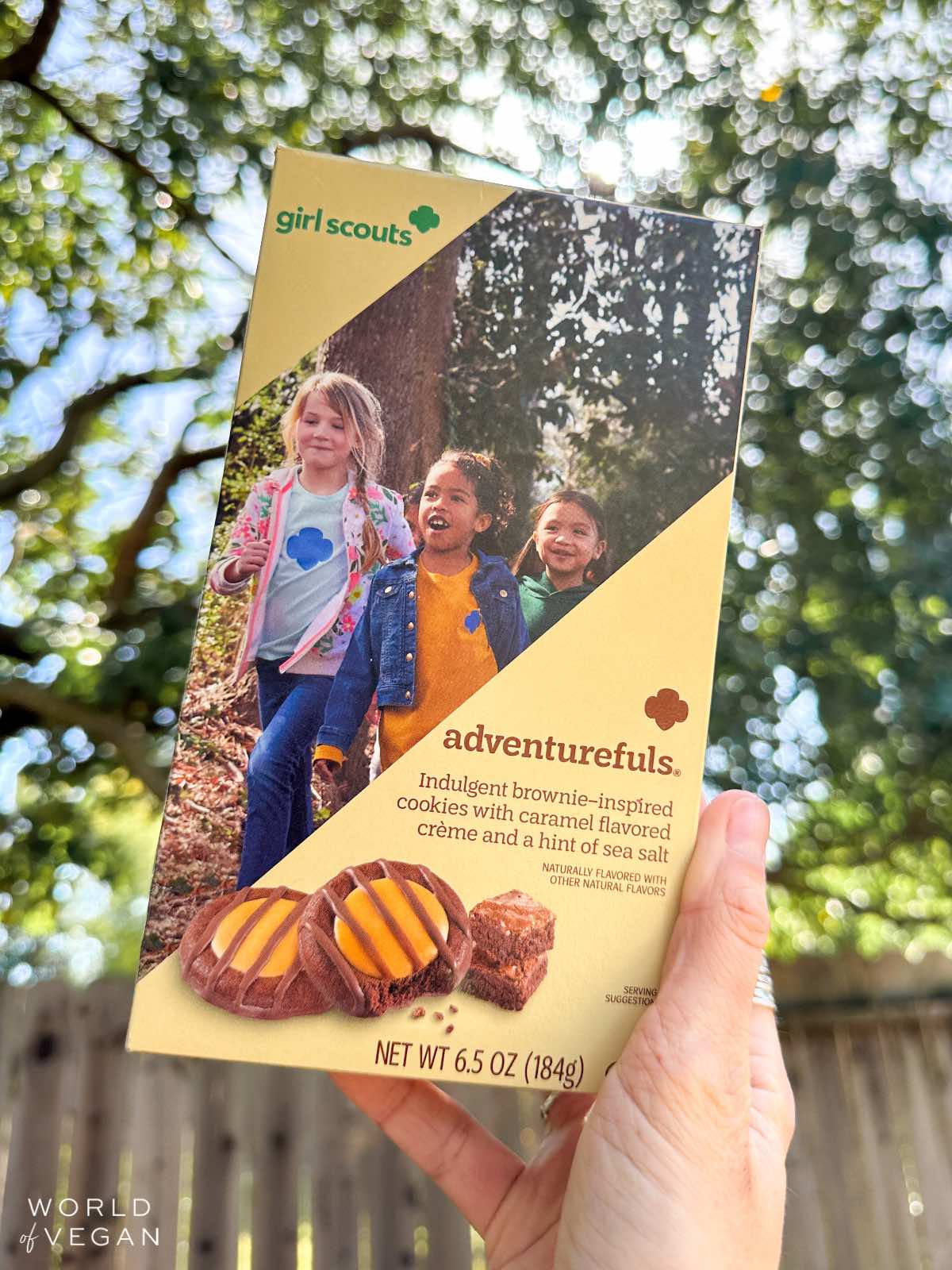 Vegan woman holding up a box of Adventurefuls Girl Scouts cookies outside.