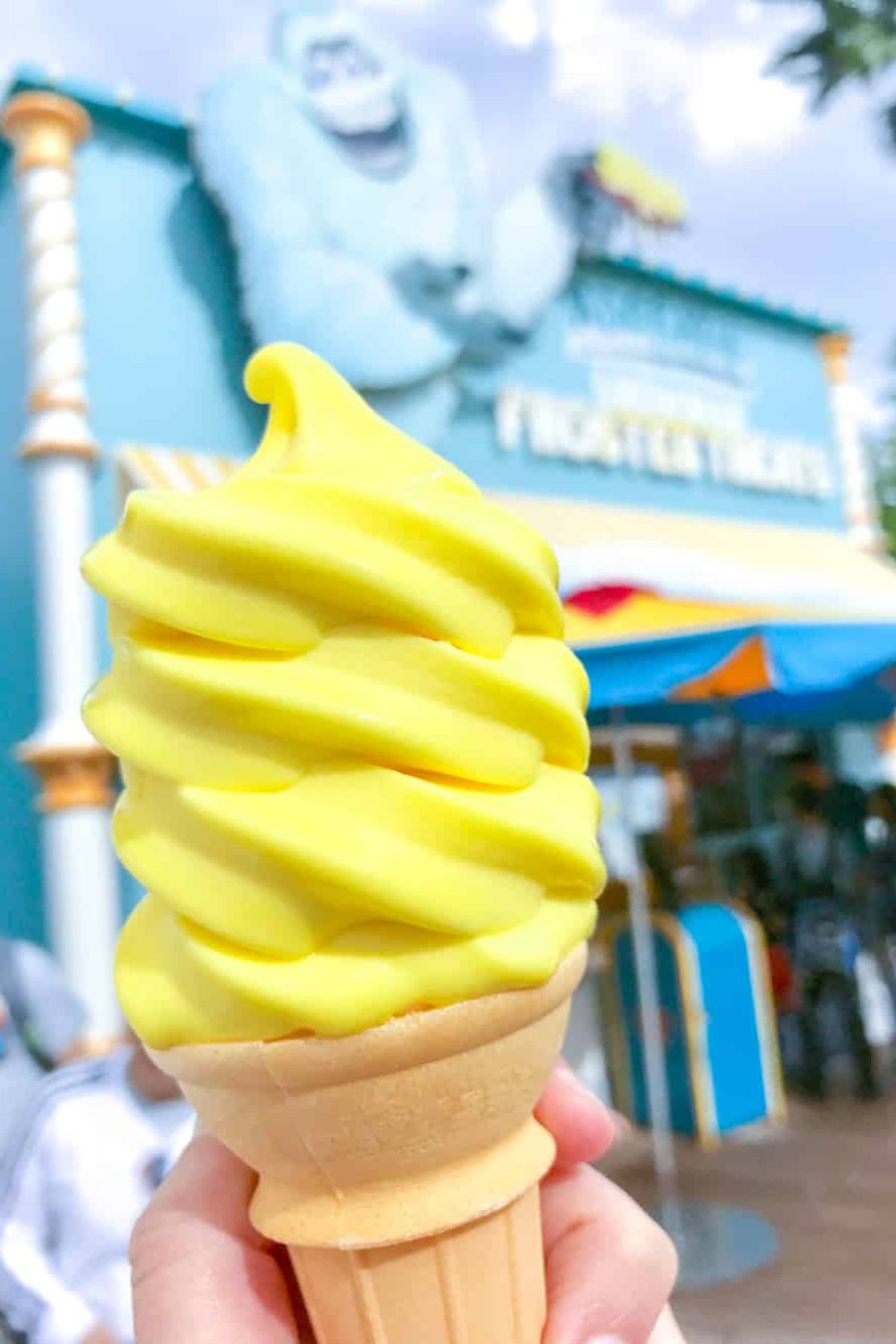 Vegan Dole Whip ice cream cone in bright yellow served at Adorable Snowman Frosted Treats in California Adventure, a refreshing and plant-based dessert.