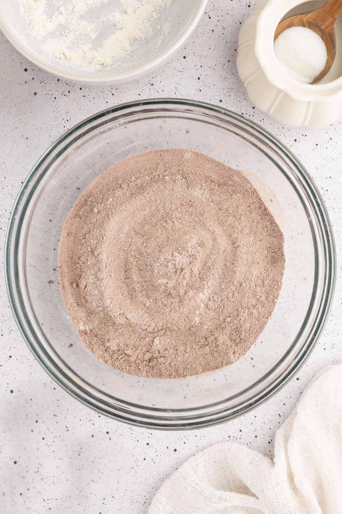 Flour, cocoa powder, baking, soda, and salt mixed together in a large glass bowl.