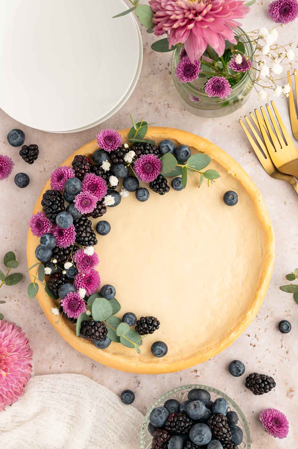 A whole vegan cheesecake topped with fresh berries and edible flowers.