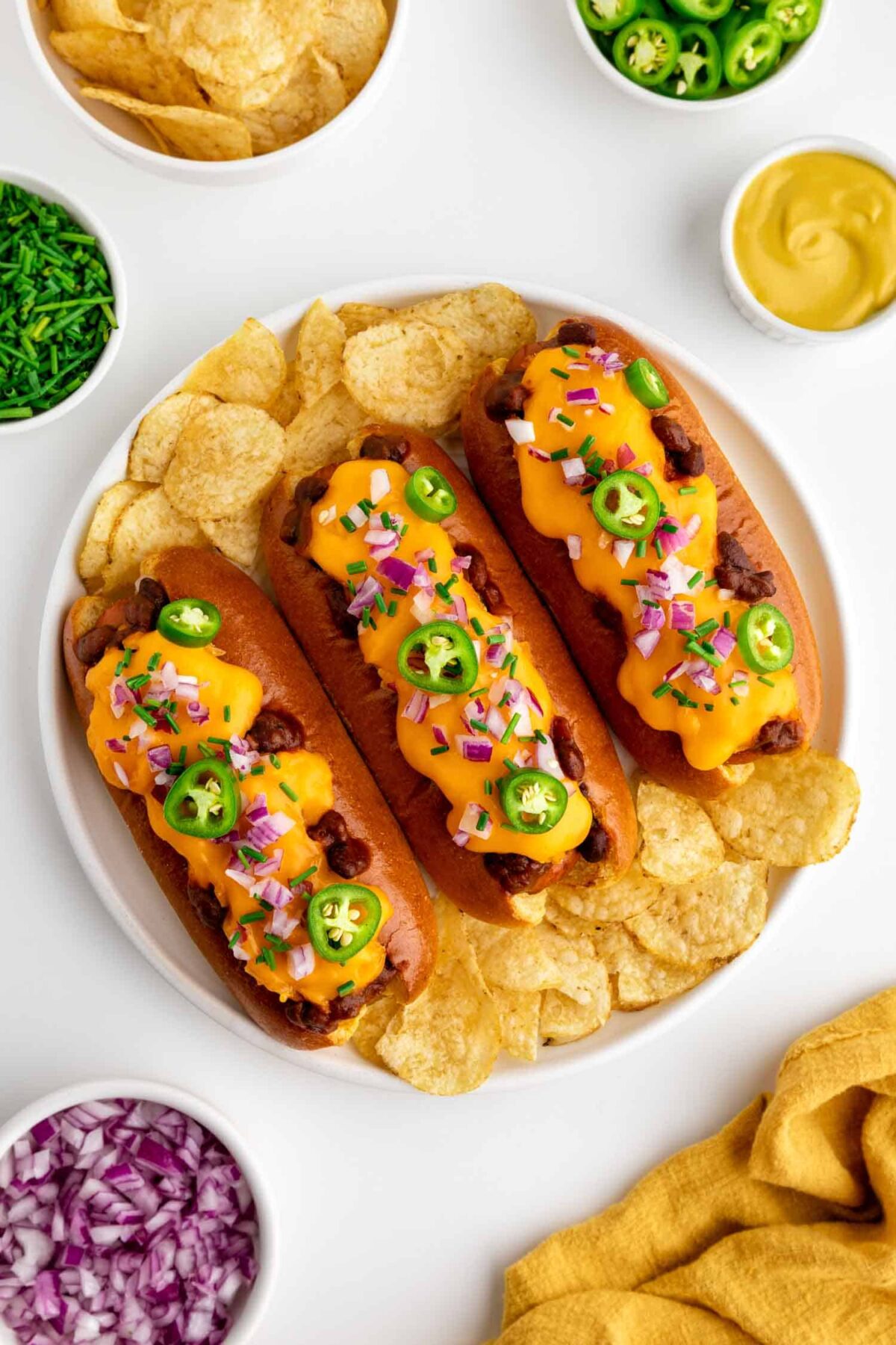 Vegan chili cheese dogs topped with melty vegan cheese and chili, perfect for summer grilling.
