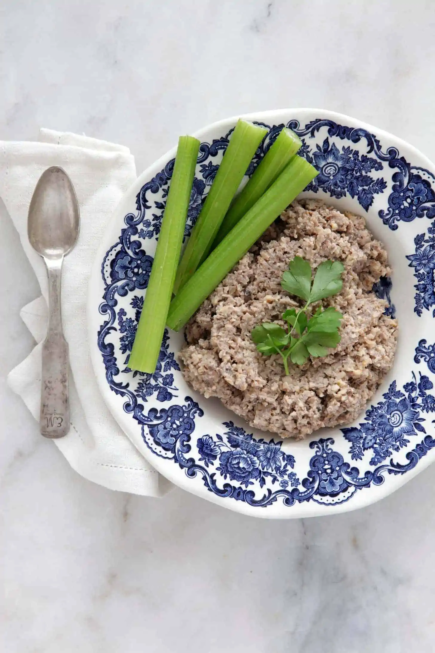 Mock chopped liver on a plate garnished with celery sticks and fresh parsley.