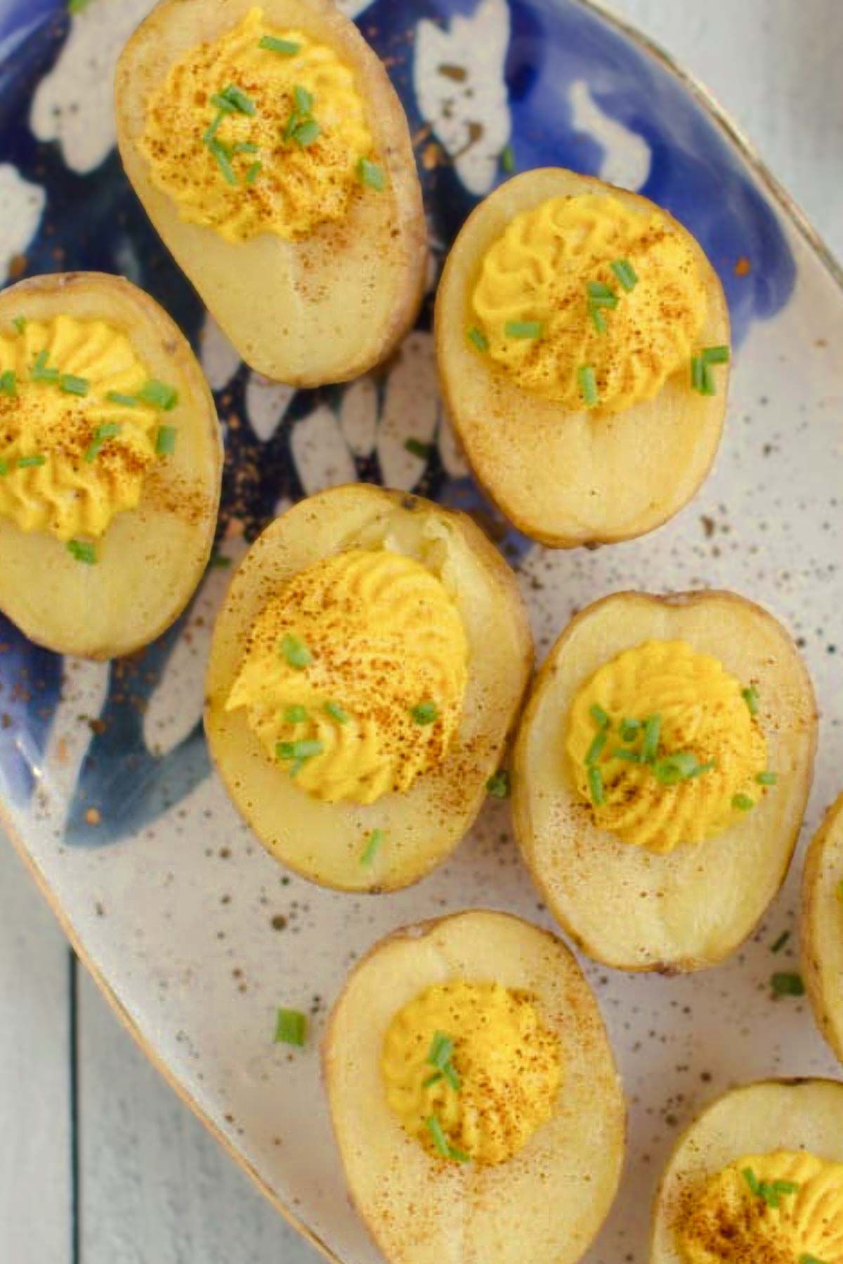 Platter of vegan deviled potatoes topped with paprika and fresh herbs, a fun twist on deviled eggs.