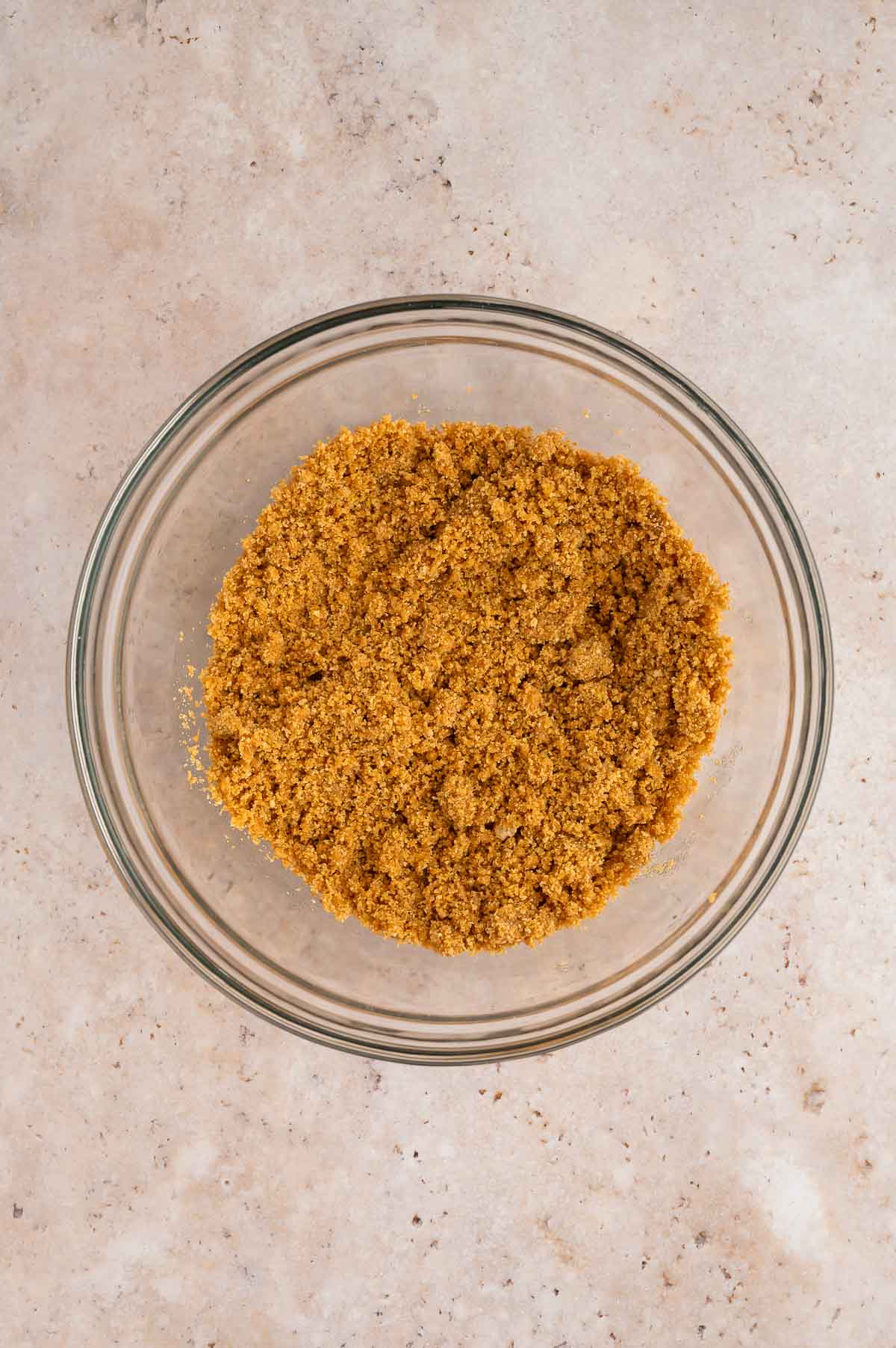 Vegan graham crackers crust batter all mixed together in a large bowl.