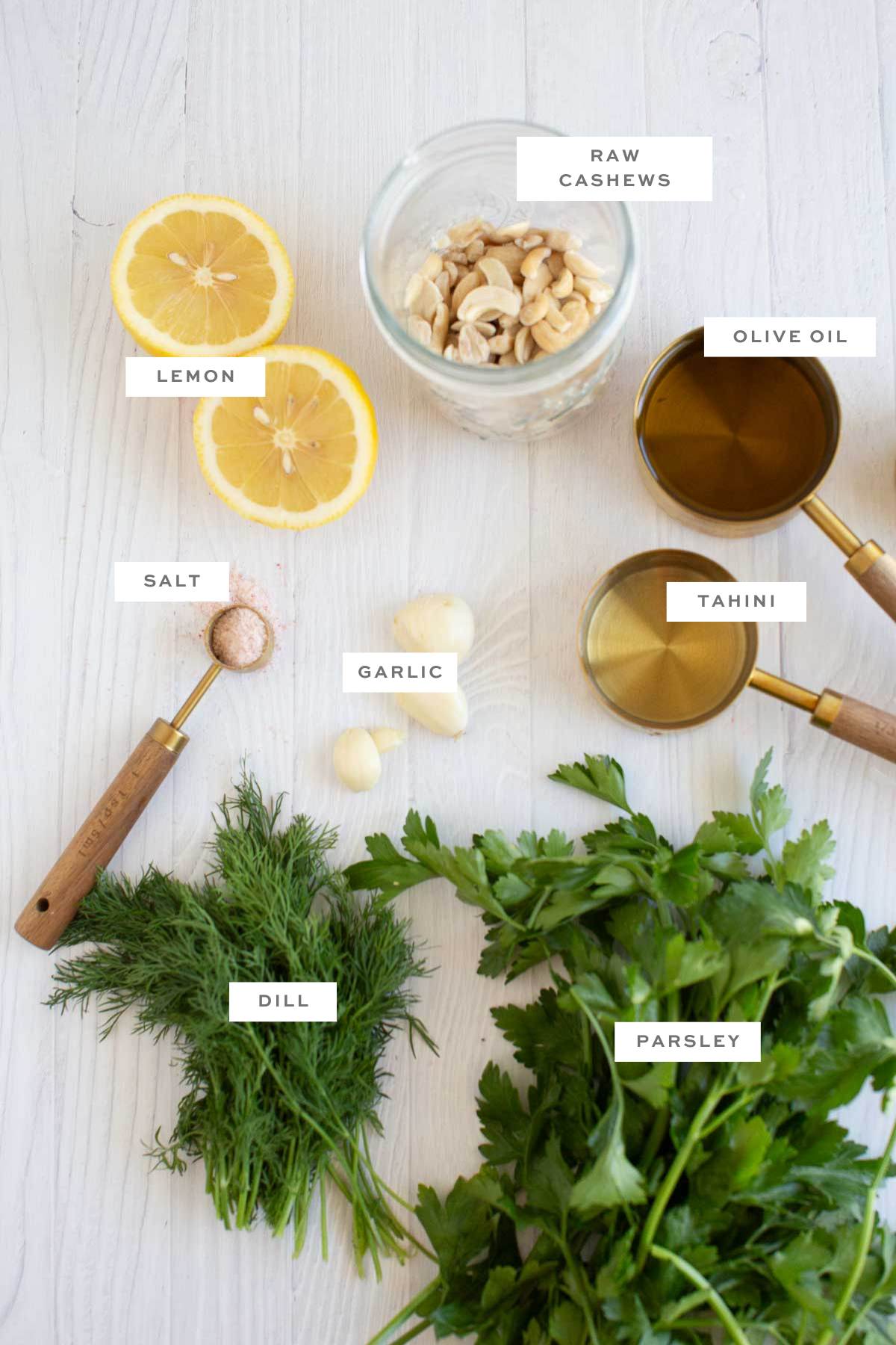 Gathered ingredients for this vegan green goddess dressing recipe laid on a flat surface with labels.