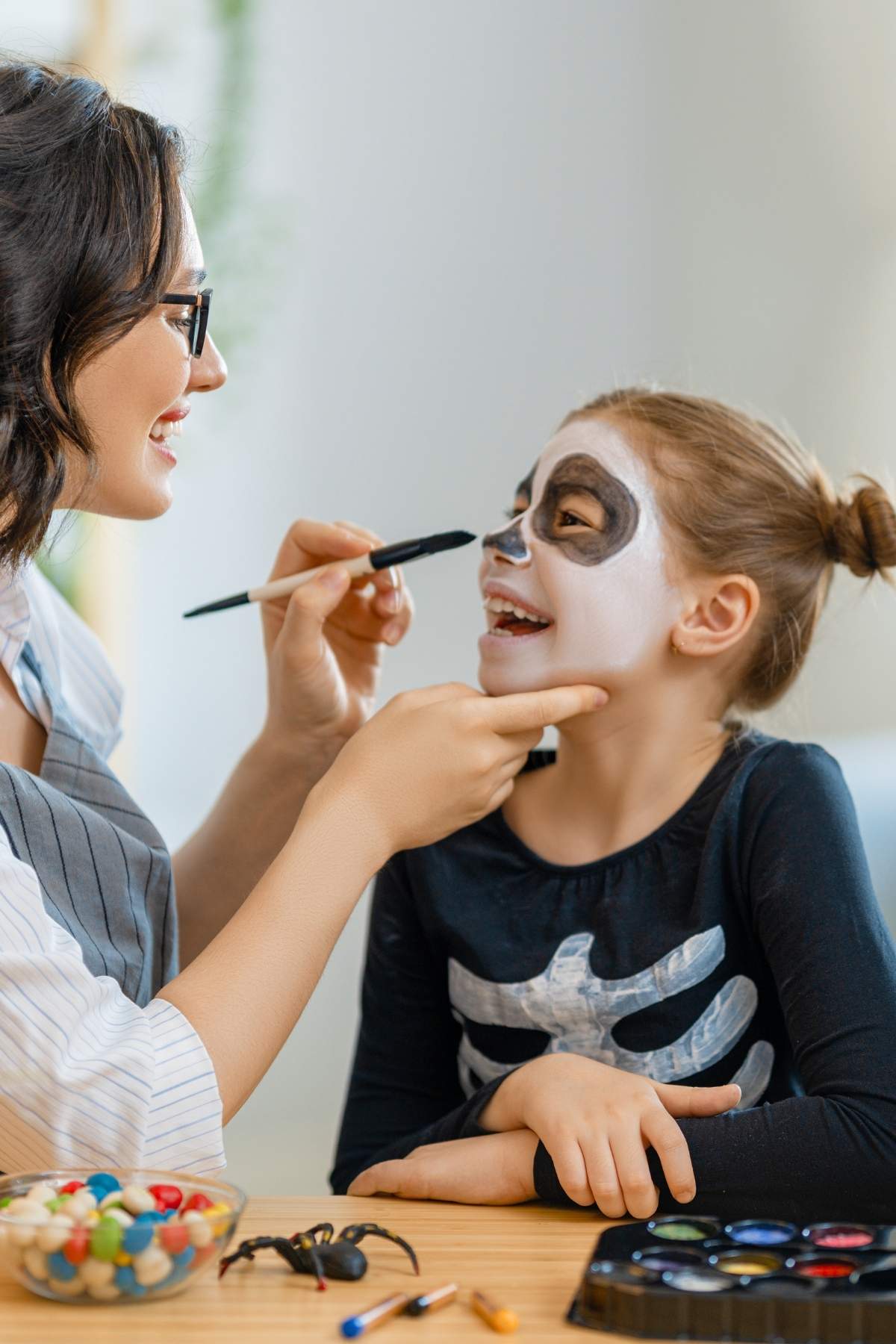 A mother putting Halloween makeup on her daughter.