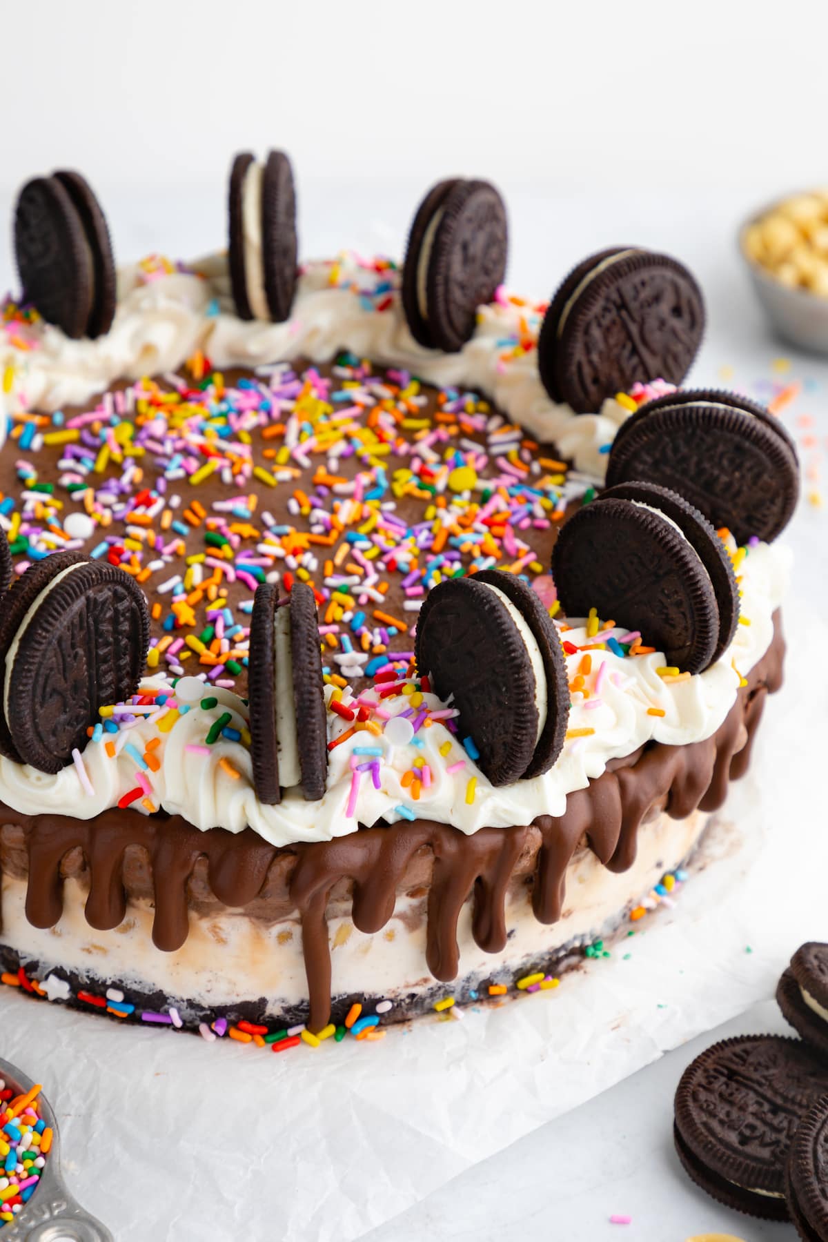 Vegan ice cream cake topped with vegan sprinkles, frosting, and Oreo cookies.