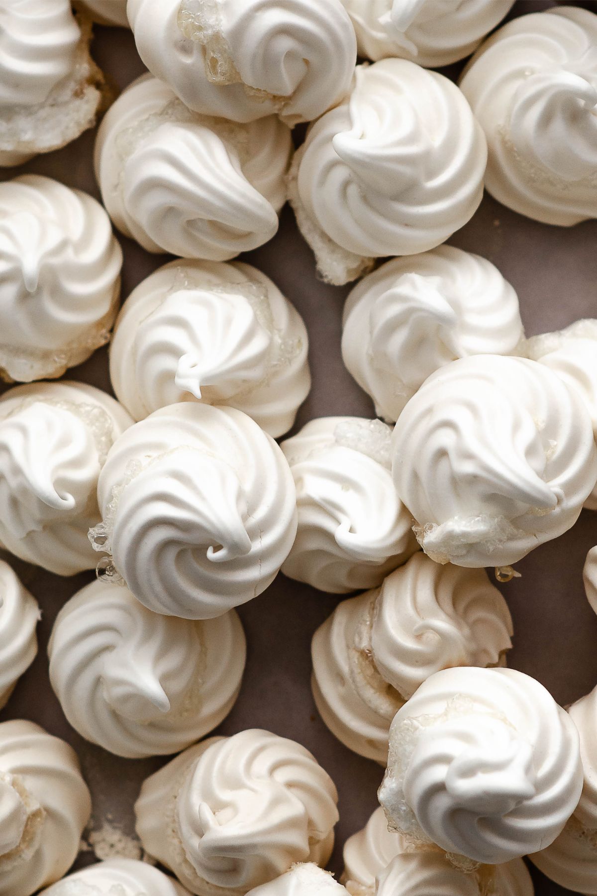 Close-up of perfectly baked vegan meringue cookies, showcasing their crisp swirled tops and delicate texture.