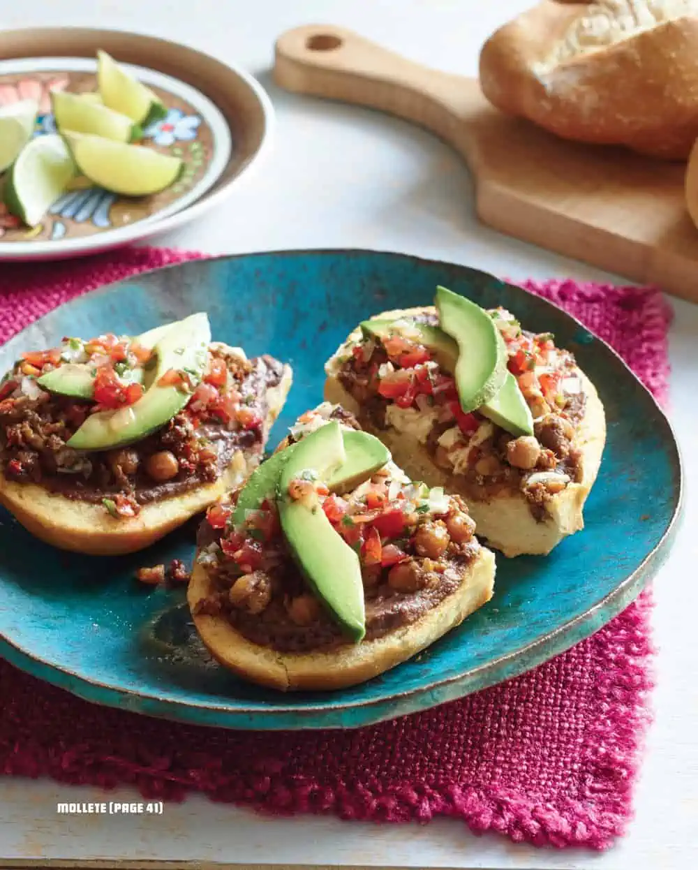 A photo of three vegan molletes topped with avocado from the book "¡Salud! Vegan Mexican Cookbook" by Eddie Garza.