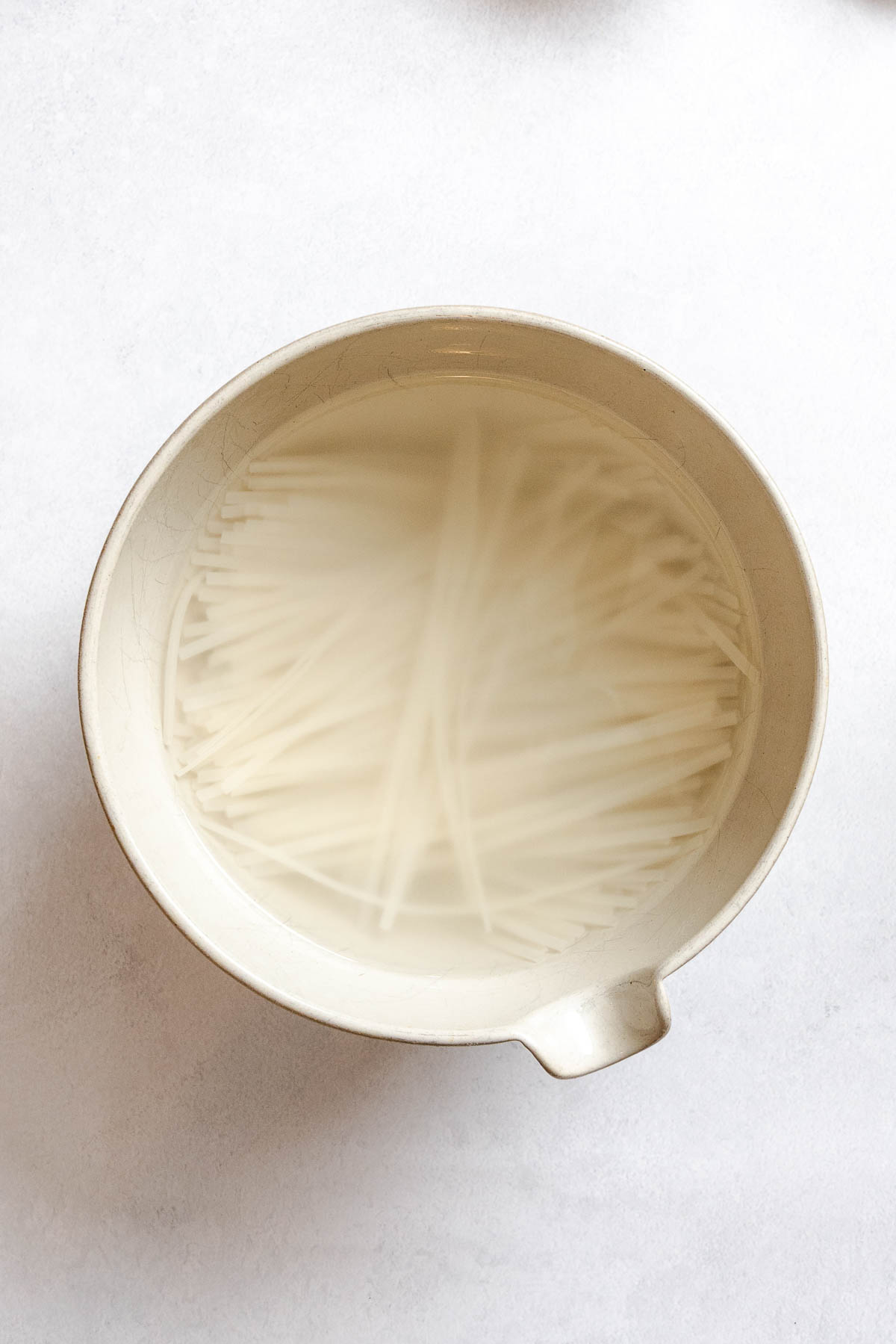 Brown rice pad Thai noodles soaking in hot water before cooking.