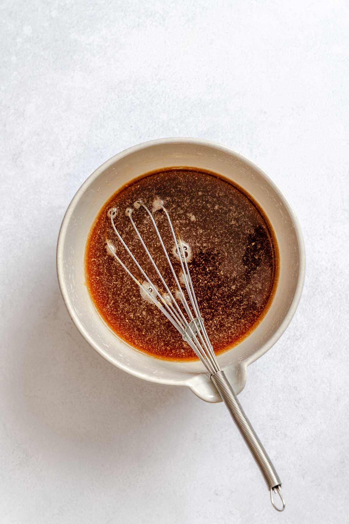 Homemade vegan pad Thai sauce whisked in a mixing bowl with soy sauce, peanut butter, and lime.