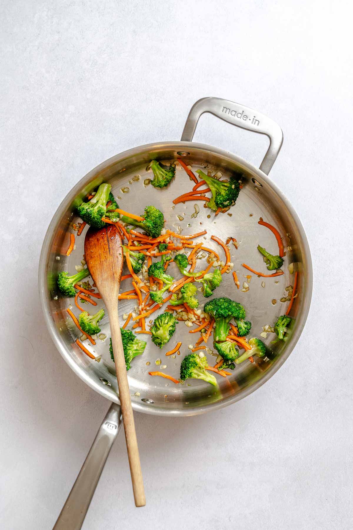 Sautéed broccoli, carrots, and garlic in a skillet as the veggie base for vegan pad Thai.