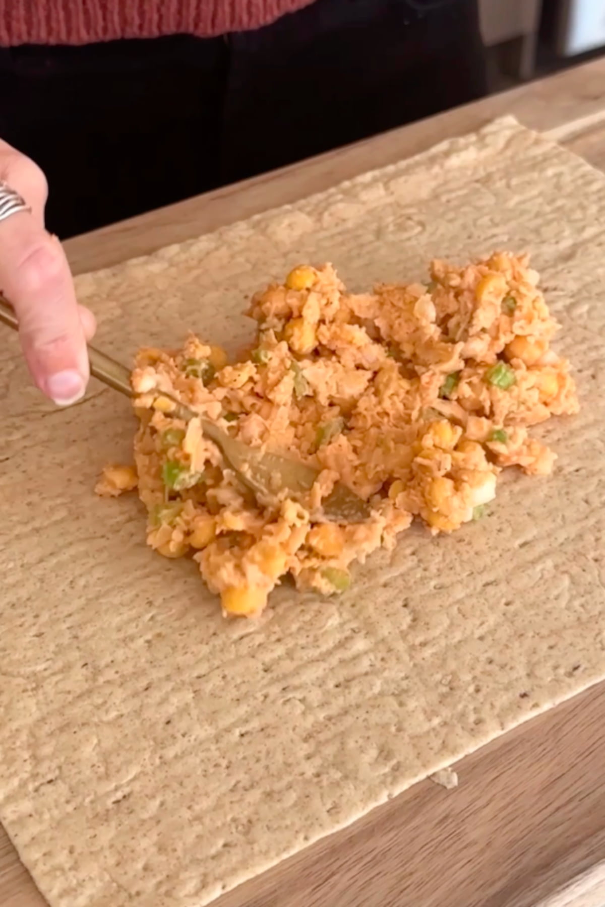 Lavash wrap on a cutting board with the chickpea mixture being spread across it.
