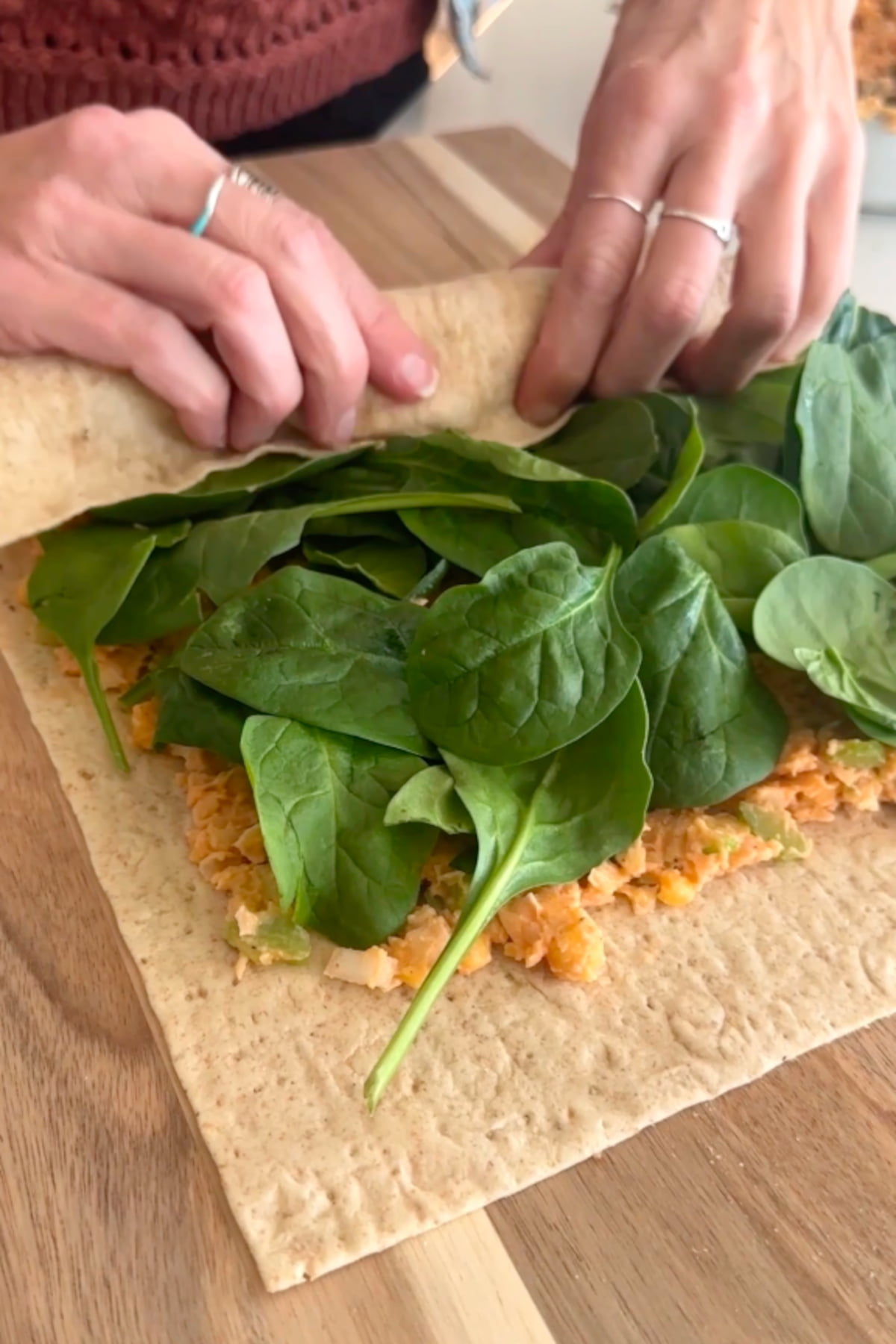 Hands rolling up the vegan pinwheel wrap.