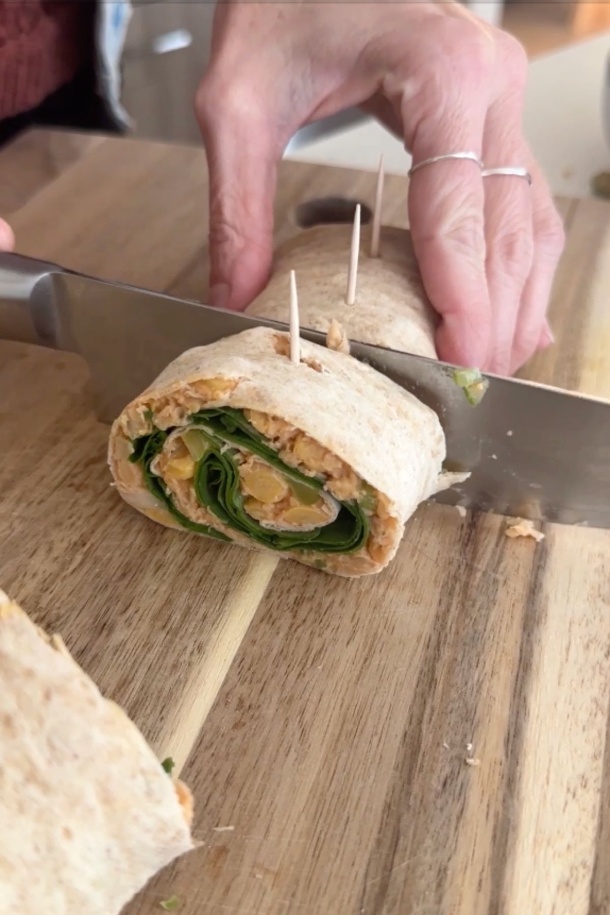 A knife slicing the roll into individual vegan pinwheels.