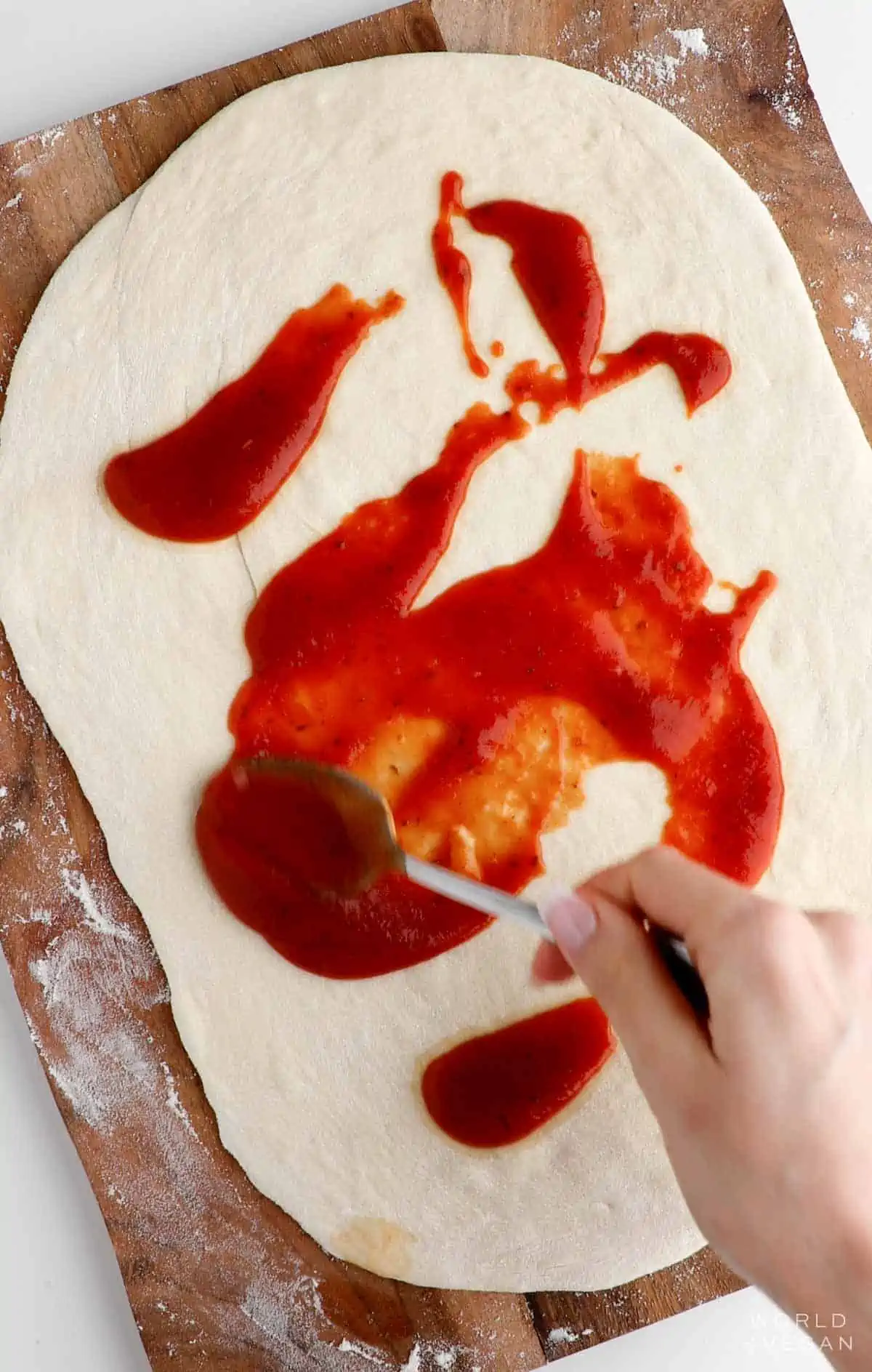 Spreading pizza sauce on dough.