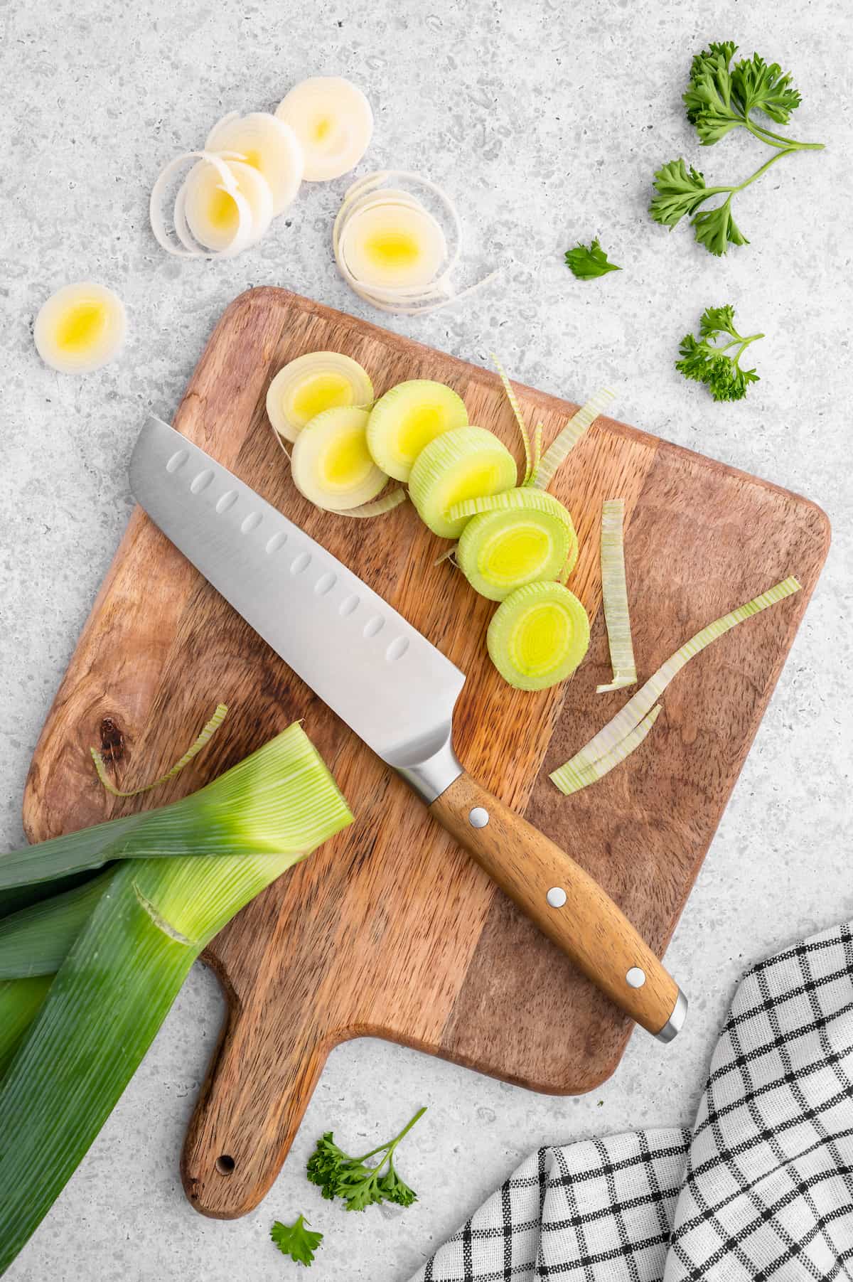 Chef's knife on a cutting board with vegetable ingredients.