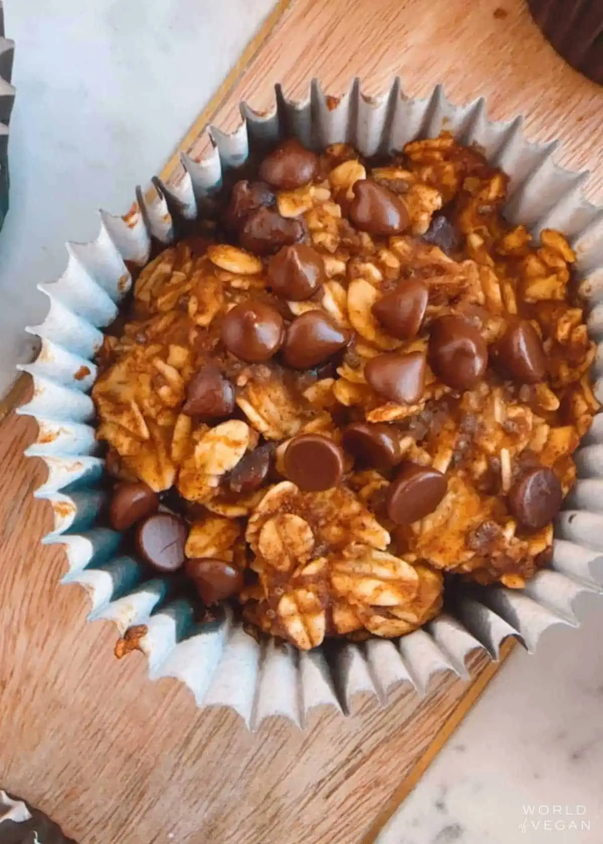 A baked oatmeal bite in a muffin pan liner, topped with lots of chocolate chips.