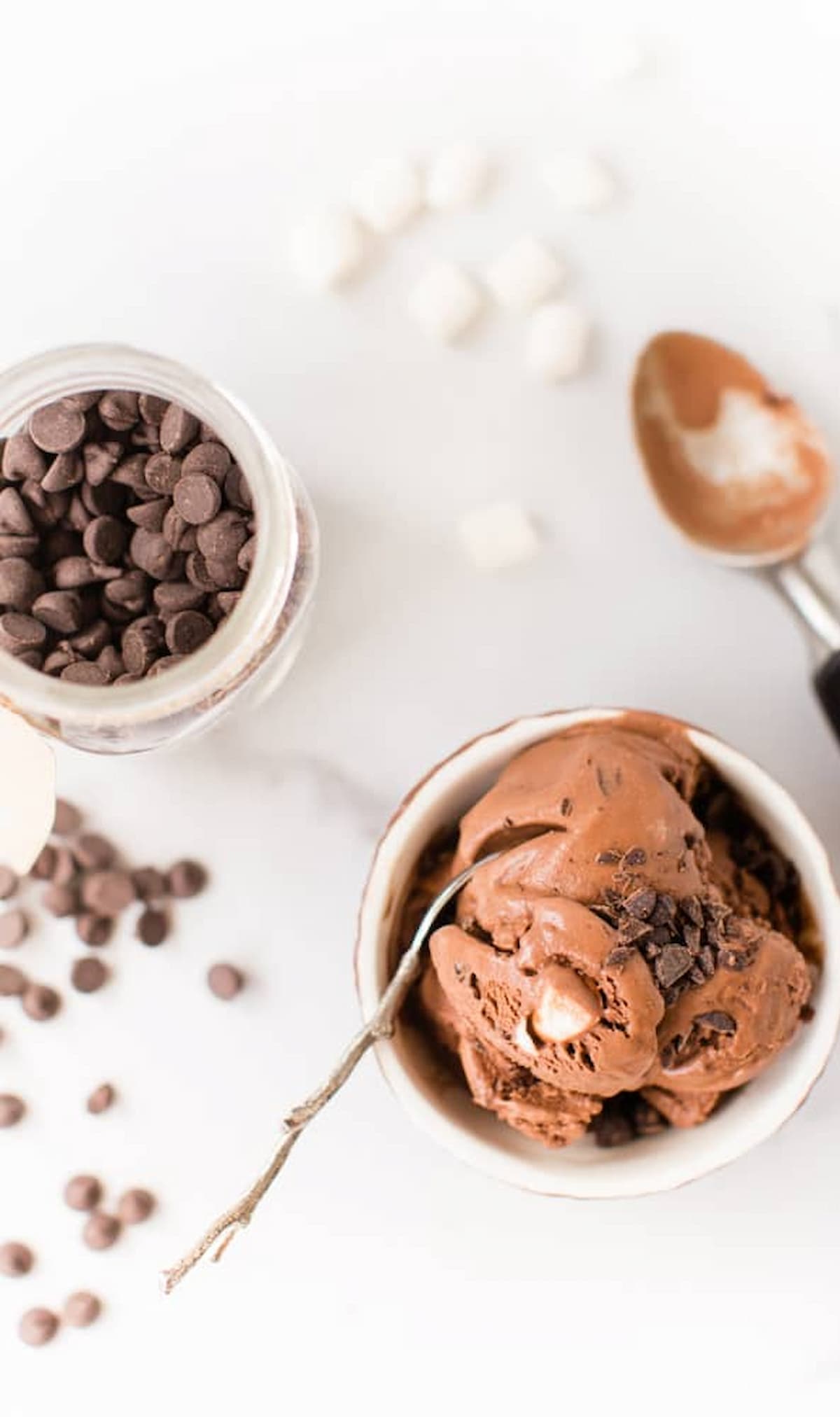 A bowl of vegan rocky road ice cream with chocolate chips and marshmallows.