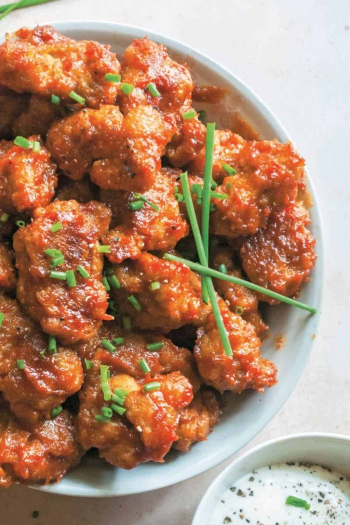 BBQ seitan wings coated in a sticky Carolina-style sauce, garnished with chives and ready to eat.