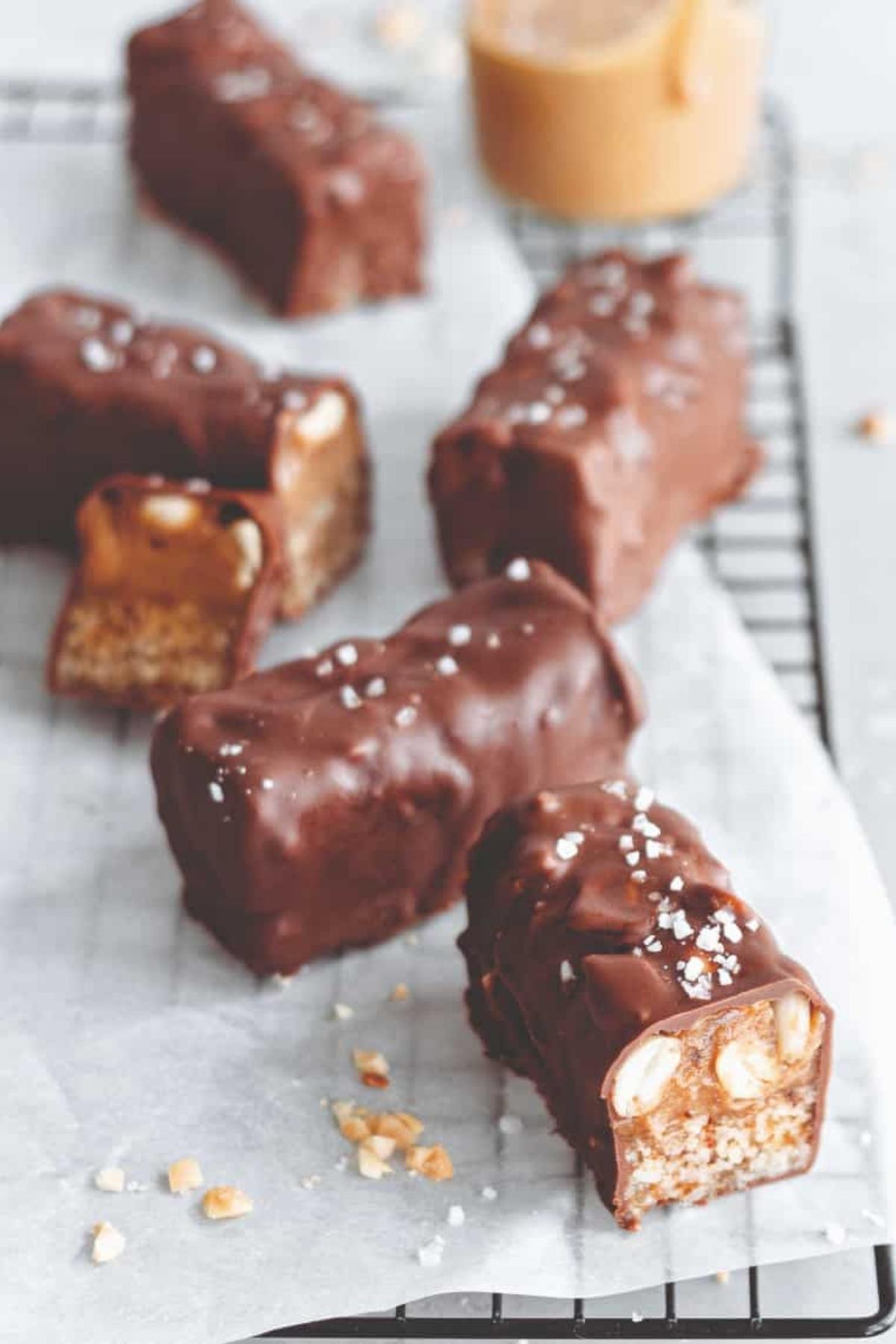 Vegan Snickers bars on a wire rack, coated in dark chocolate with a sprinkle of sea salt.