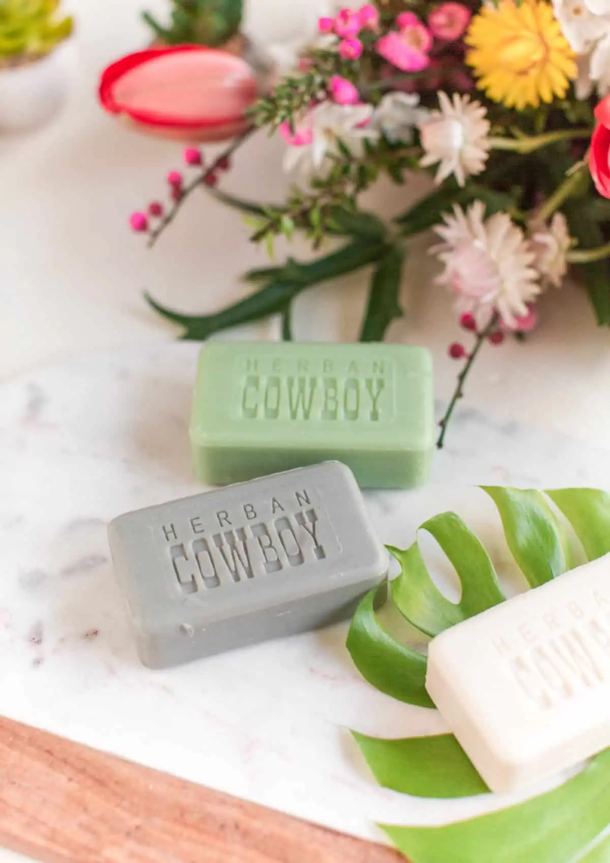 Bars of vegan soap next to flowers.