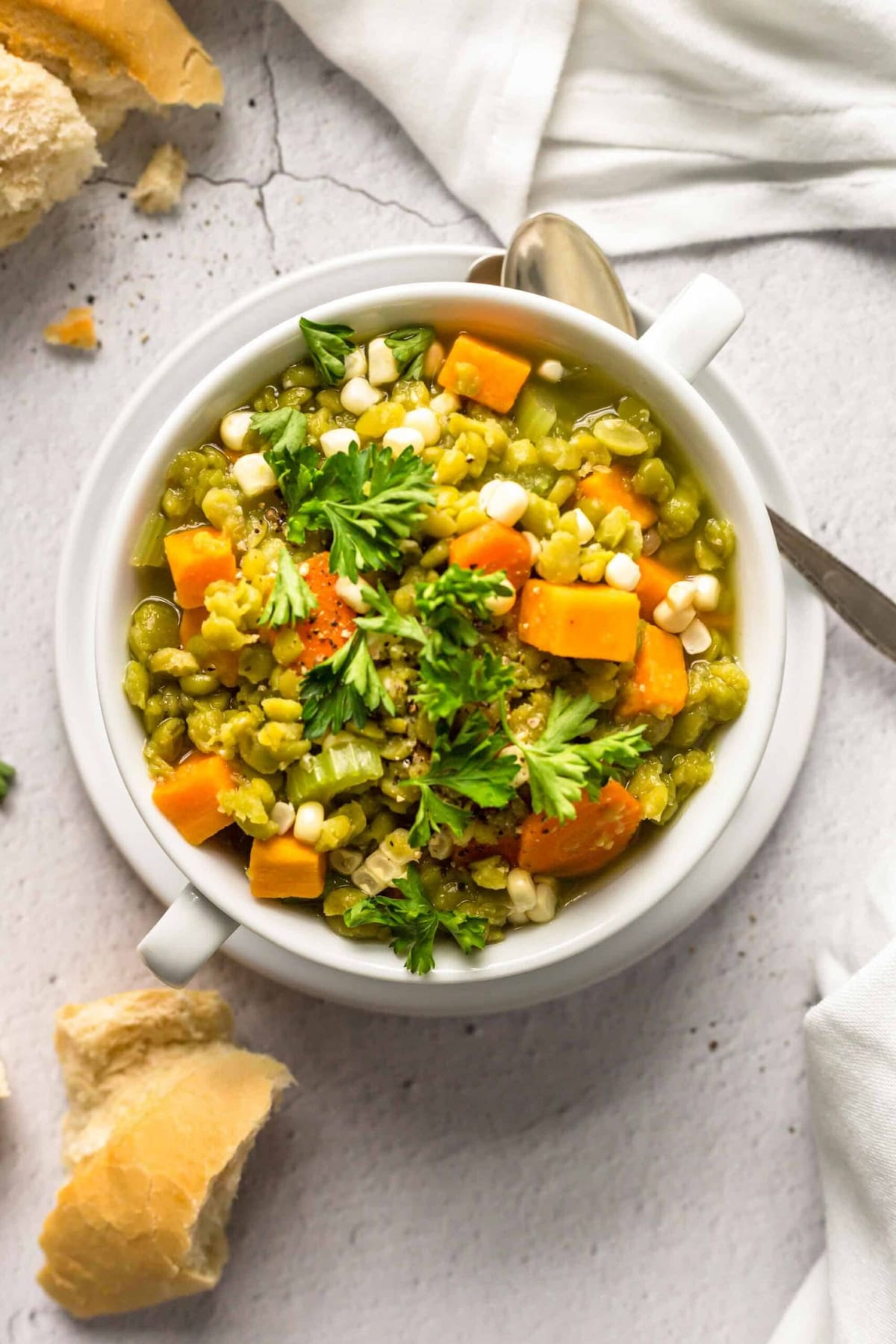 Warming bowl of vegan split pea soup with sweet potatoes in a white bowl on top of a white plate.