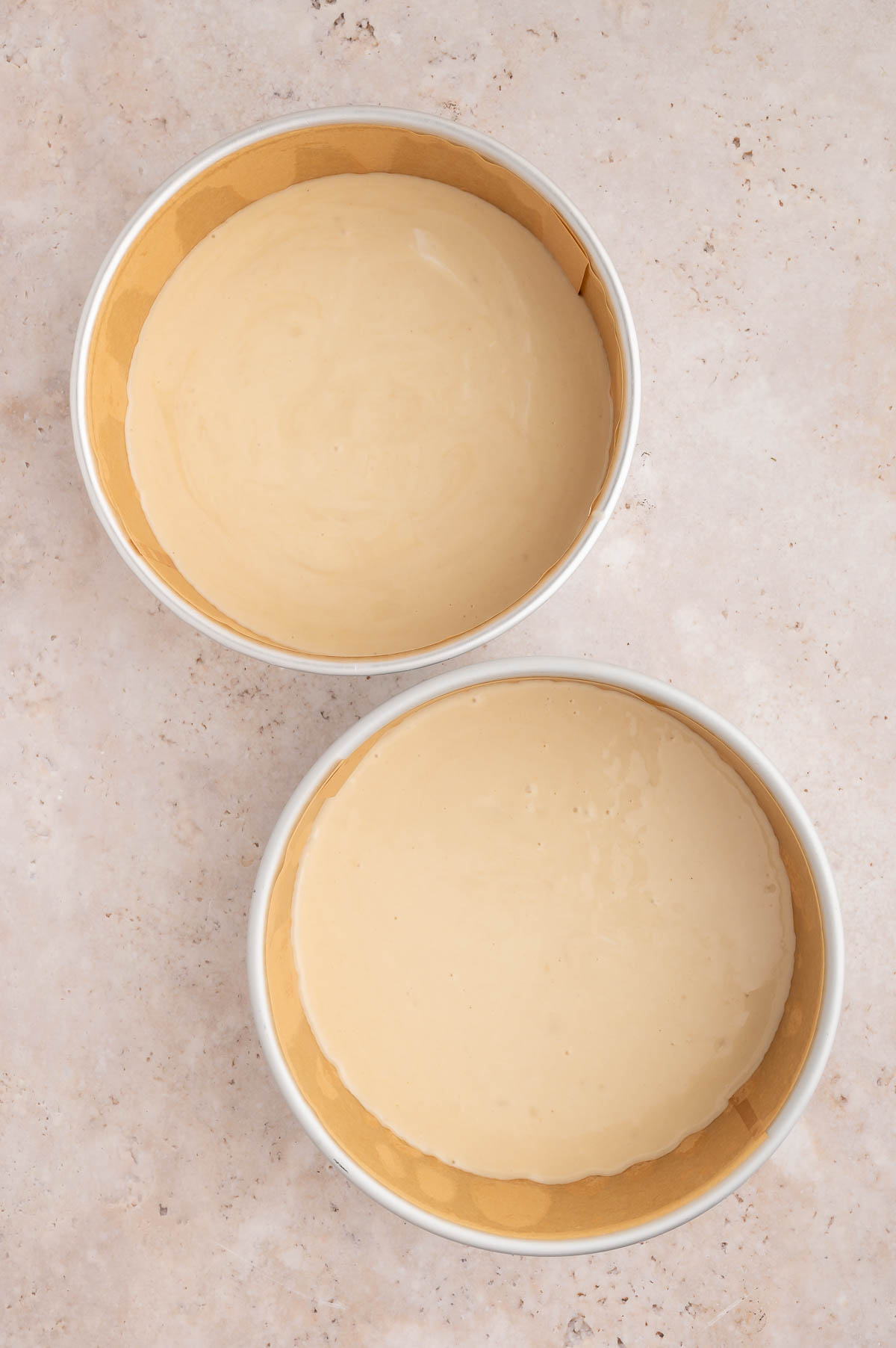 Vegan strawberry shortcake batter divided into two lined cake pans.