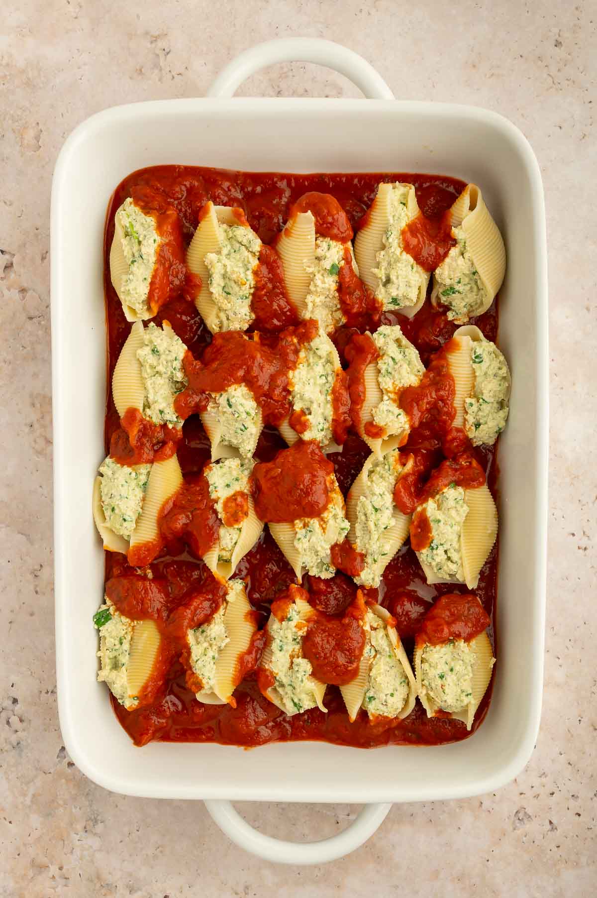 Plant-based ricotta-stuffed shells in a casserole dish before being baked.