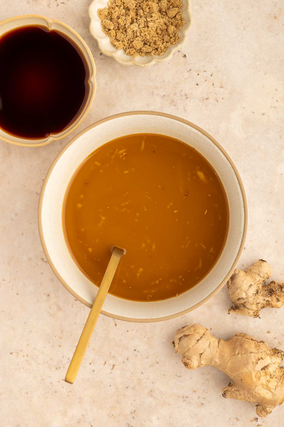 Glossy vegan teriyaki sauce in a bowl with ginger, brown sugar, and soy sauce on the side.