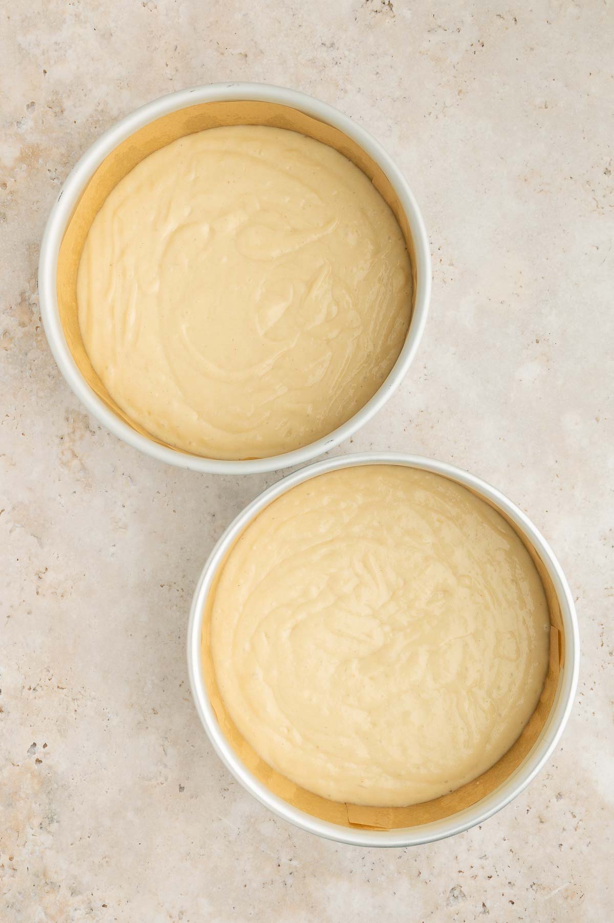 Two pans of batter sit on a counter.