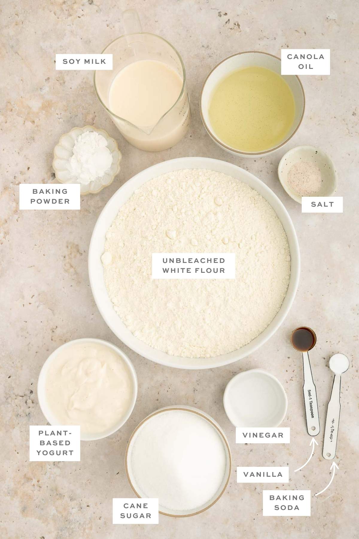 The ingredients for a homemade vegan vanilla cake with labels for each ingredient.