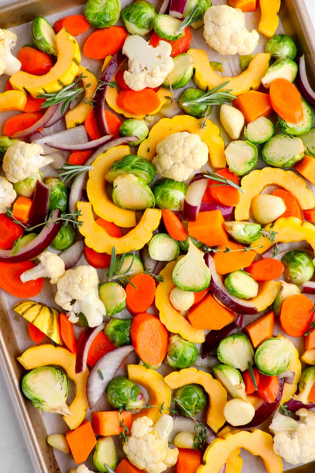 Seasoned sheet pan veggies spread out on a baking tray.